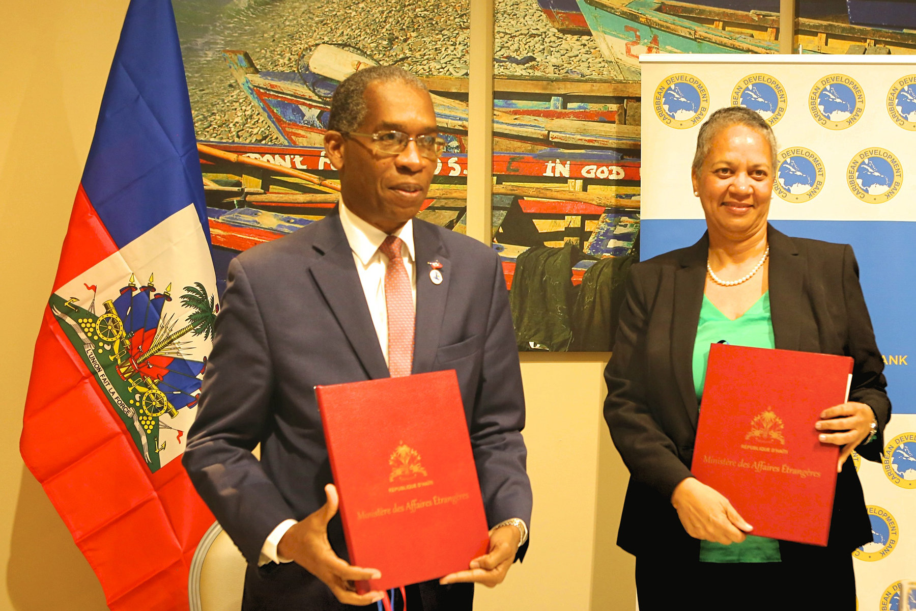 Haiti’s Minister of Foreign Affairs, His Excellency Antonio Rodrigue (left) and Vice-President (Operations), Caribbean Development Bank (CDB), Monica La Bennett (right), hold the signed country agreements after signing them on February 27, 2018. CDB will establish its first country office in the Republic of Haiti this year.