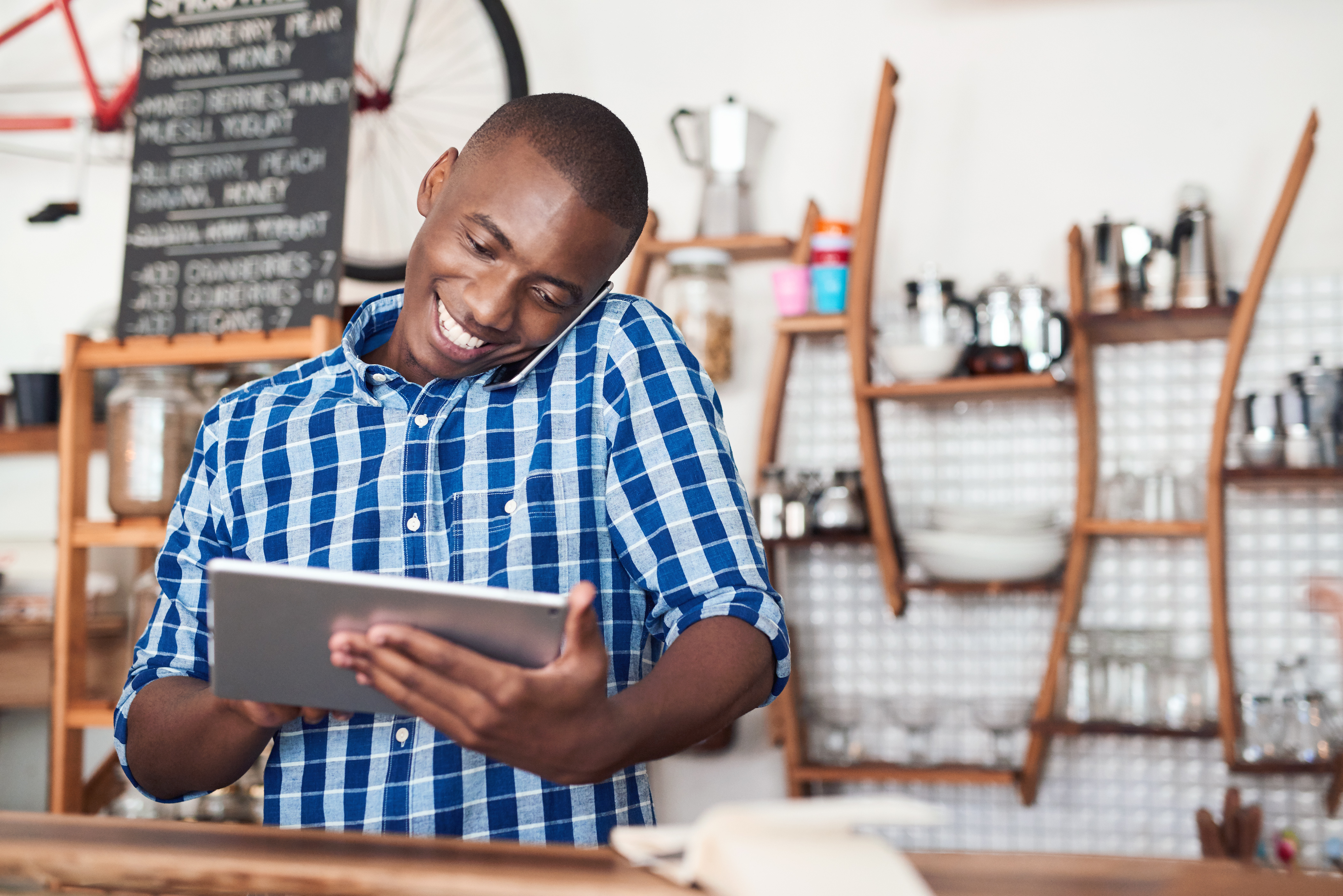 black male entrepreneur using a tablet device in a blue and white plaid shirt