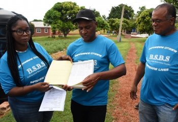 President of the Bull Savannah farmers’ group, Tracey Powell, showing a logbook with two group members