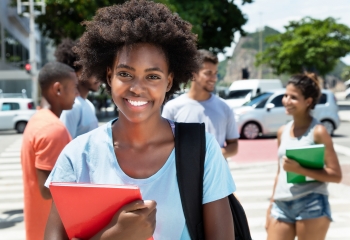 Smiling young woman with Afro hairstyle holding notebook.