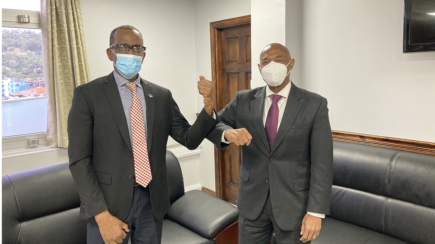 CDB President with dark suit and burgundy tie and Saint Lucian Prime Minister Philip J. Pierre with dark suit and red/white plaid tie greeting with elbow bumping, both wearing face masks