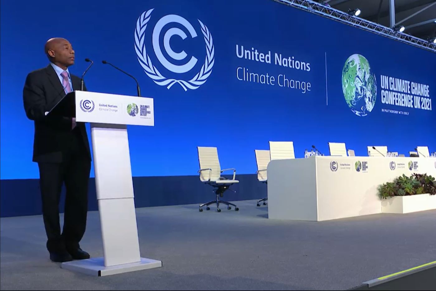 CDB President Dr Gene Leon at lectern with blue background with UN Climate Change Conference