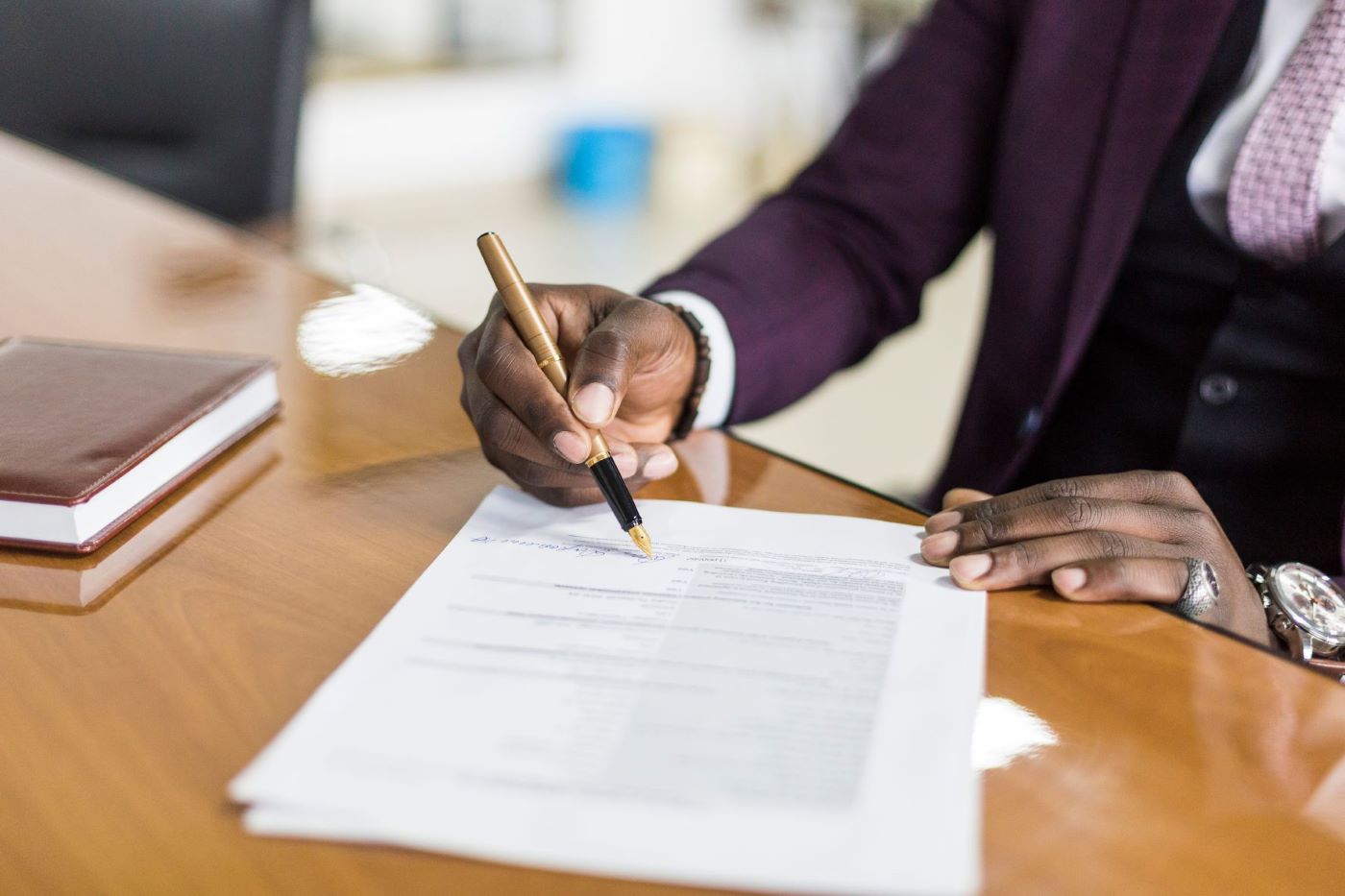 Arm of man in purple suit writing on document