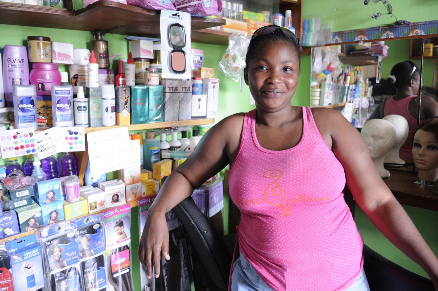 Young female business owner in pink blouse standing inside of store