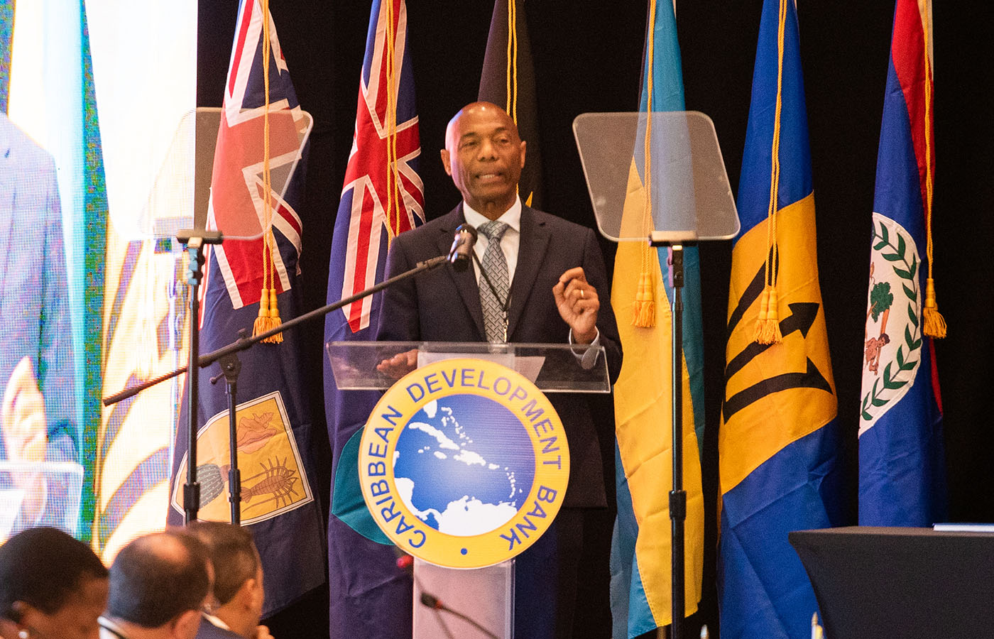 President Leon standing at lectern delivering remarks with member countries flags in the background