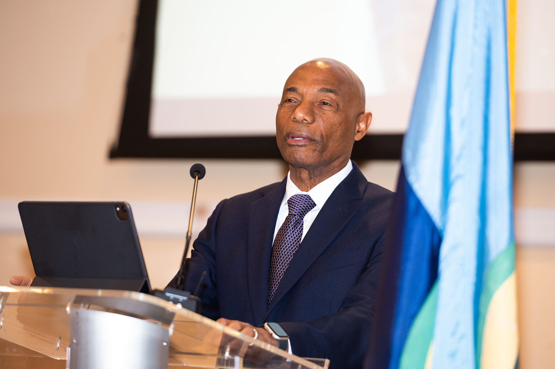 gentleman in dark suit delivering lecture at lectern