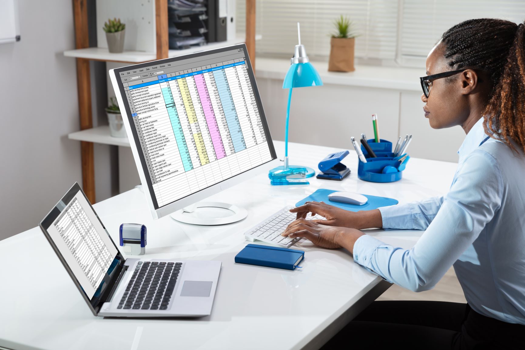 woman with braids sitting at computer looking at spreadsheets