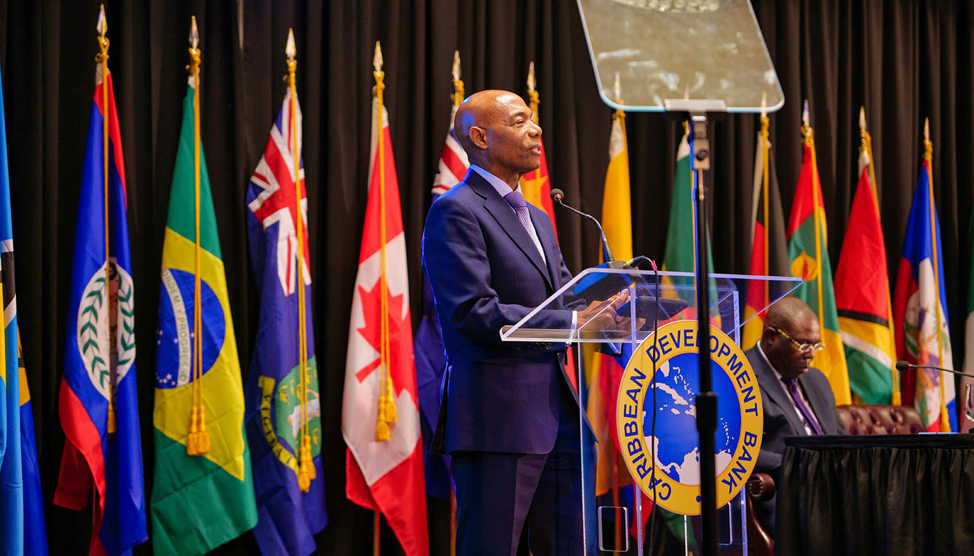 CDB President standing at lectern with member flags in the background