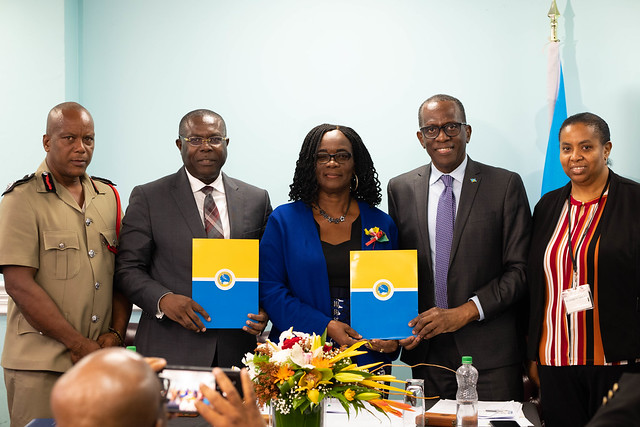 Five people including the VPO of the Caribbean Development Bank Isaac Solomon and the president of Saint Lucia Phillip J Pierre are standing holding folders 
