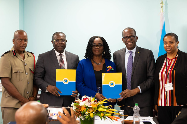 Five people including the VPO of the Caribbean Development Bank Isaac Solomon and the president of Saint Lucia Phillip J Pierre are standing holding folders