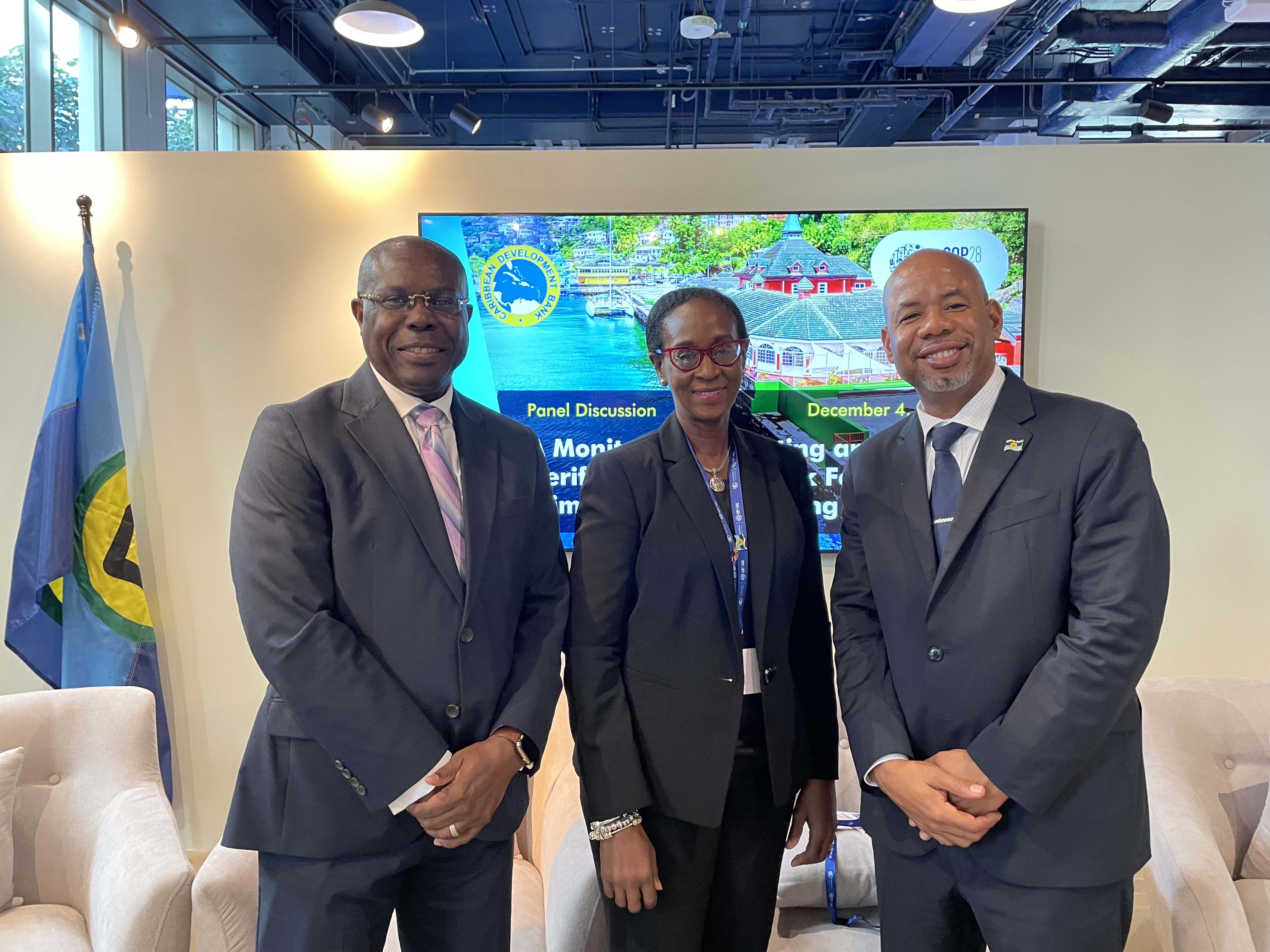 three persons in business suits standing looking into camera, the middle one is a black woman, those flanking are two black men