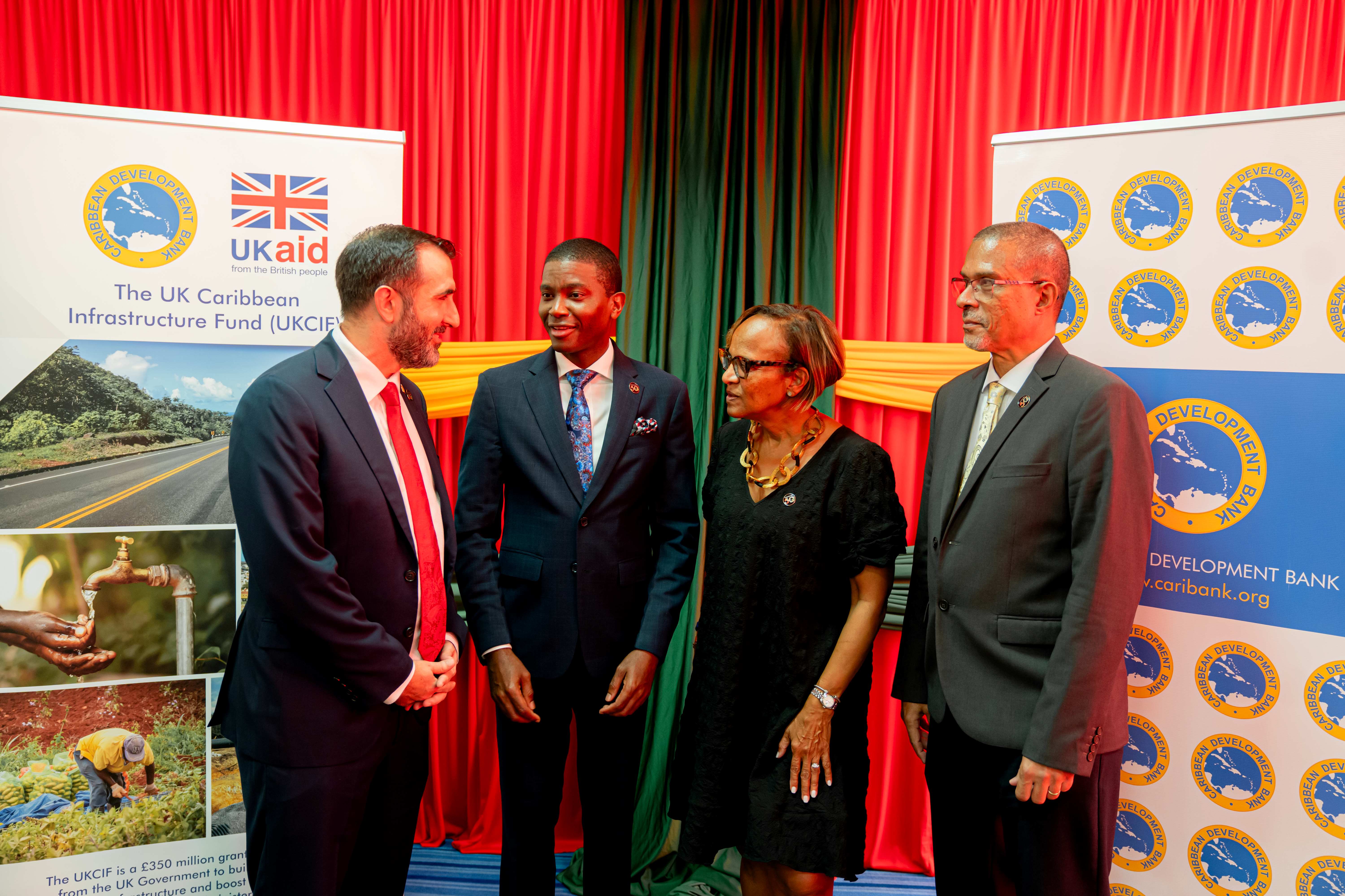 Four people, three men and one woman are standing looking and speaking 