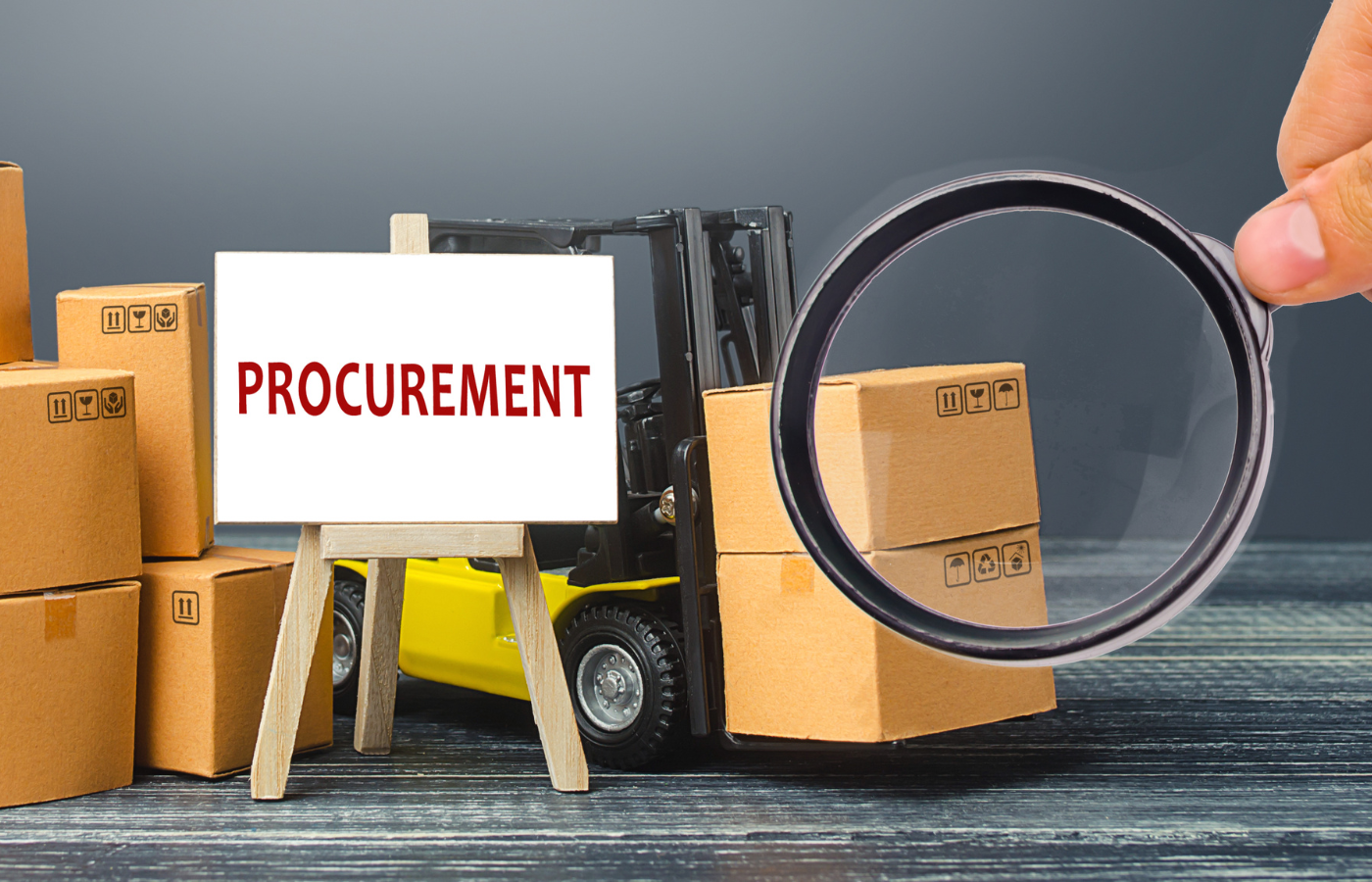 image of forklift with boxes and boxes stacked to the left with the word procurement on a white easel