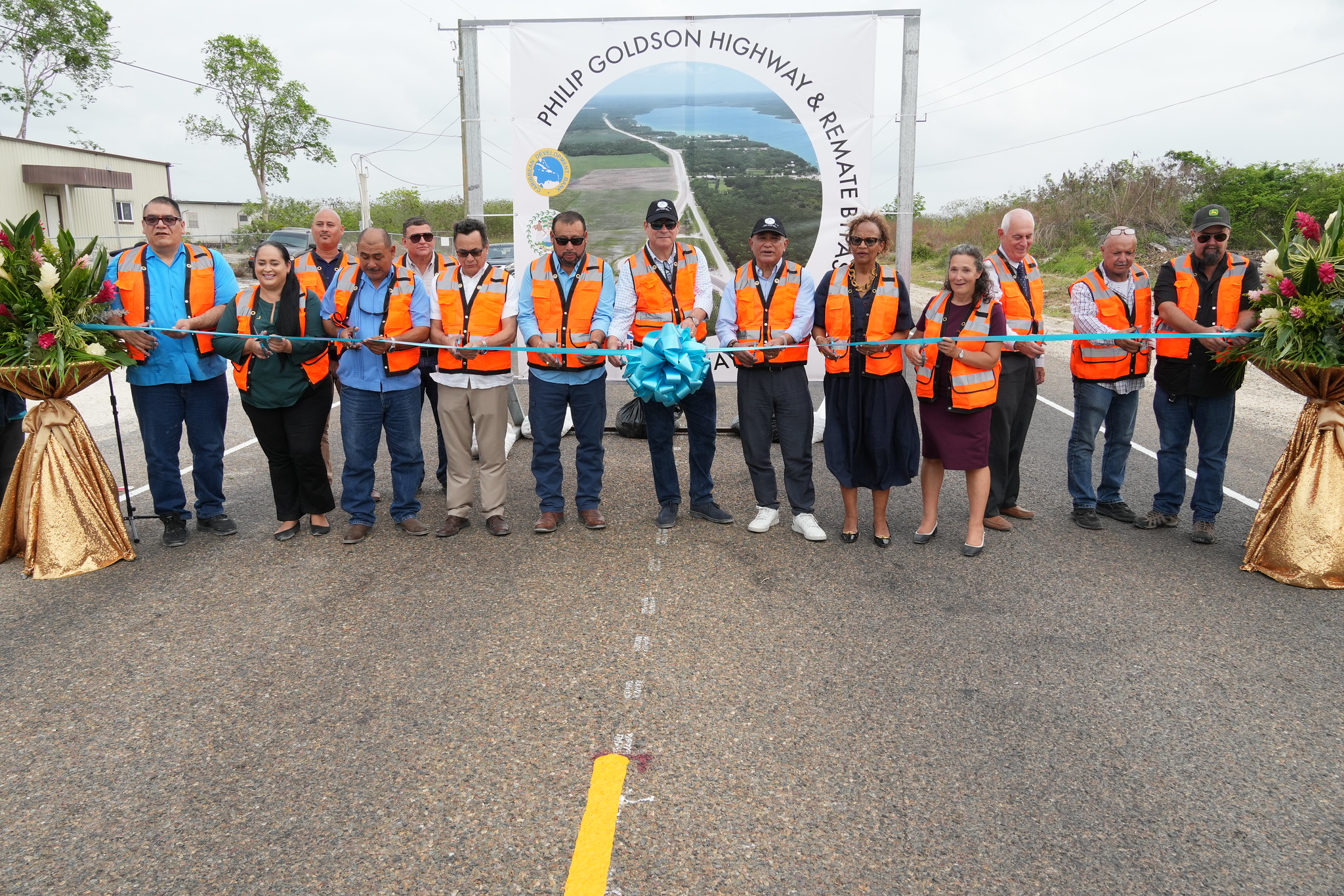 Group of persons behind long ribbon opening new road in Belize 