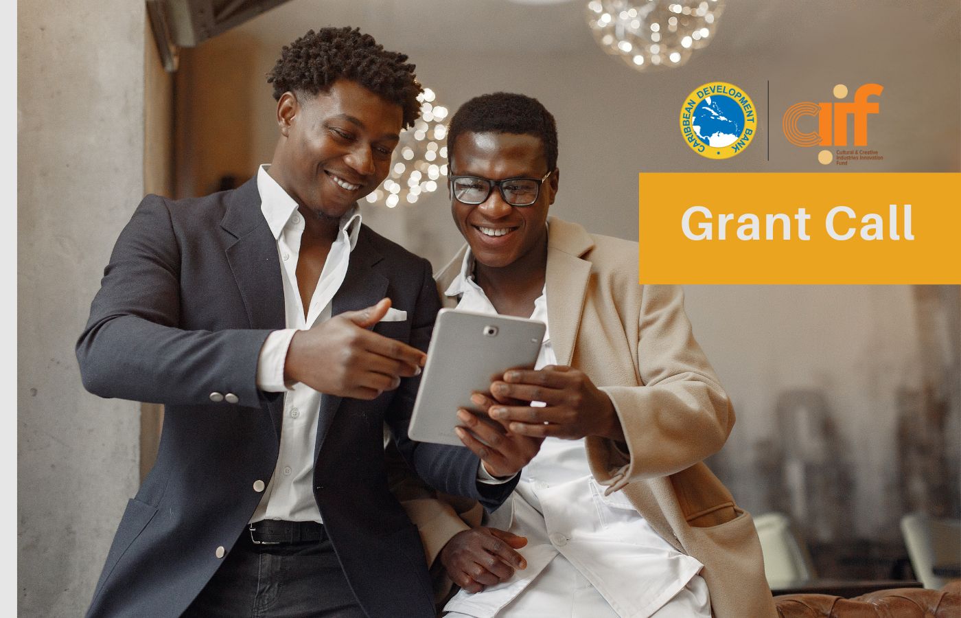 two black male entrepreneurs standing looking at a tablet smiling in business attire