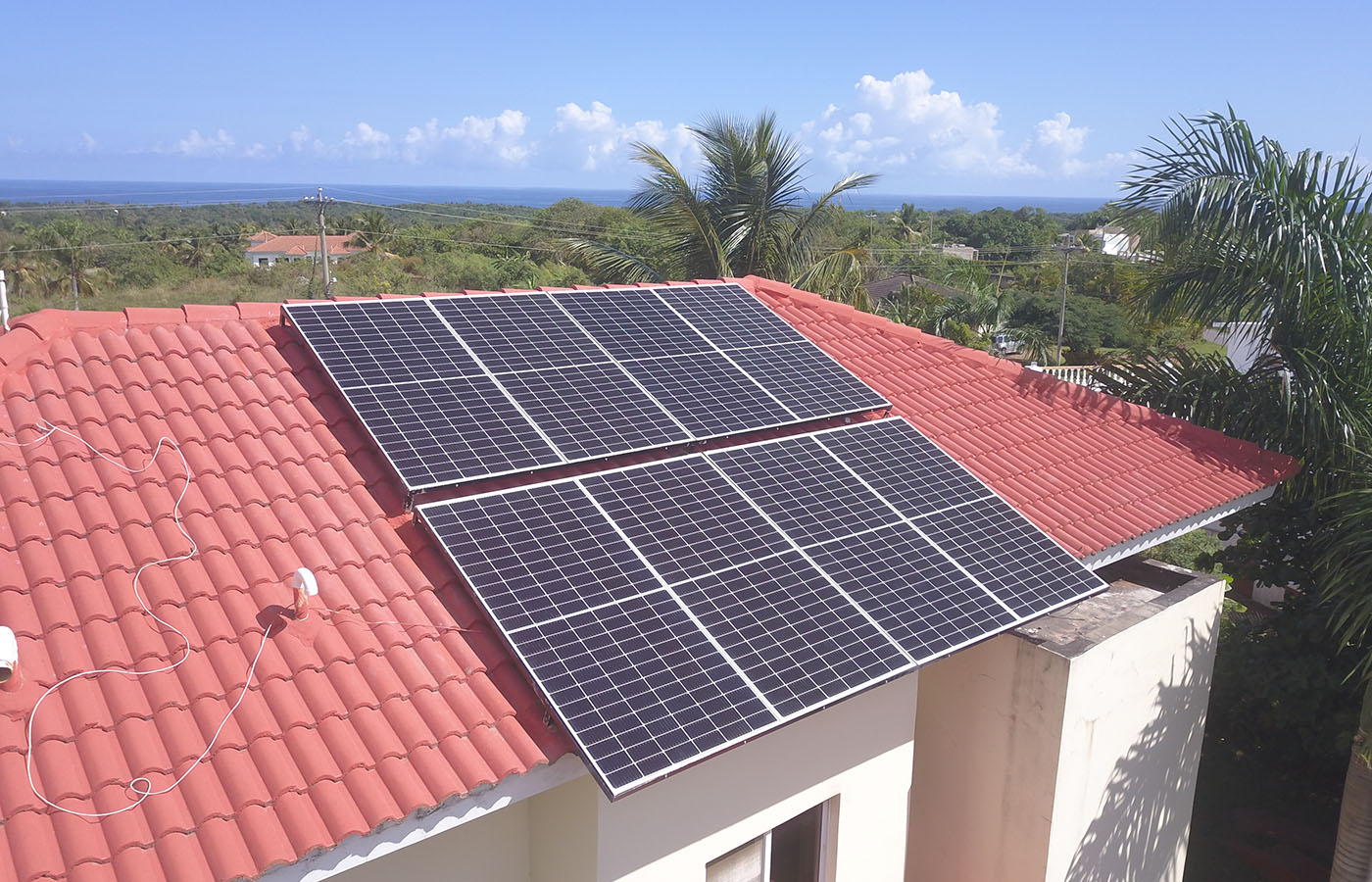 Monocrystalline solar panels 445W installed on roof of building in Caribbean with sea visible in background