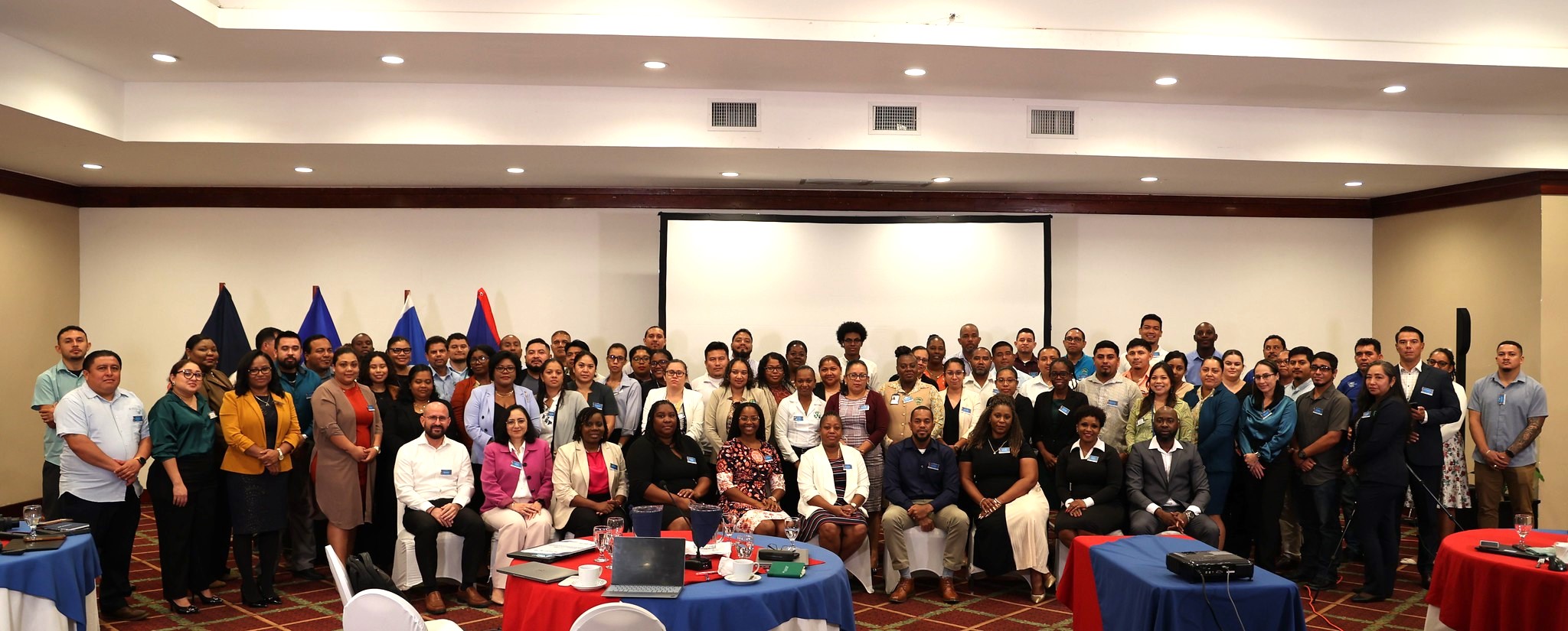 large group of persons sitting and standing a room smiling
