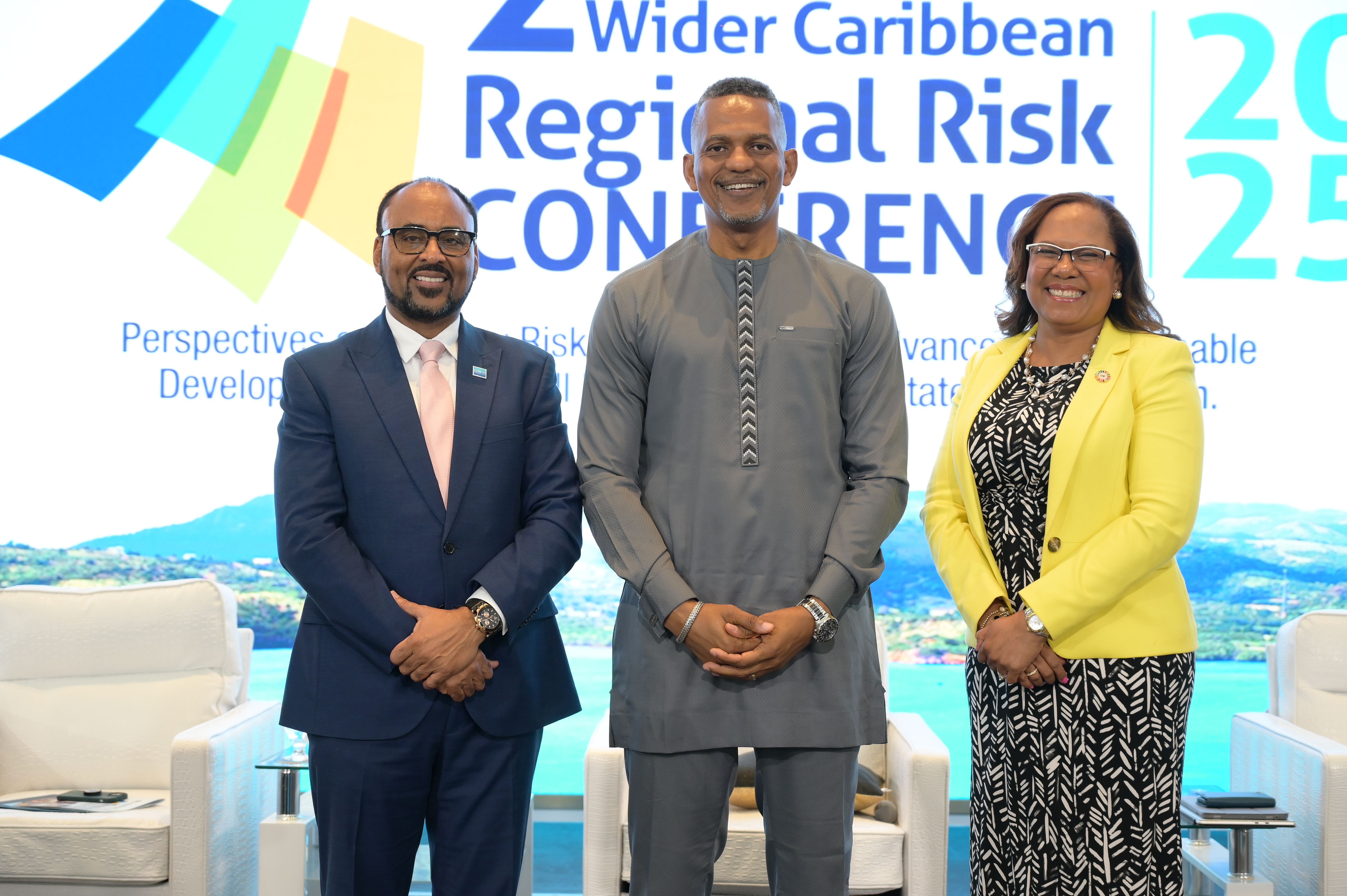 Two males and one woman standing on stage smiling in business attire