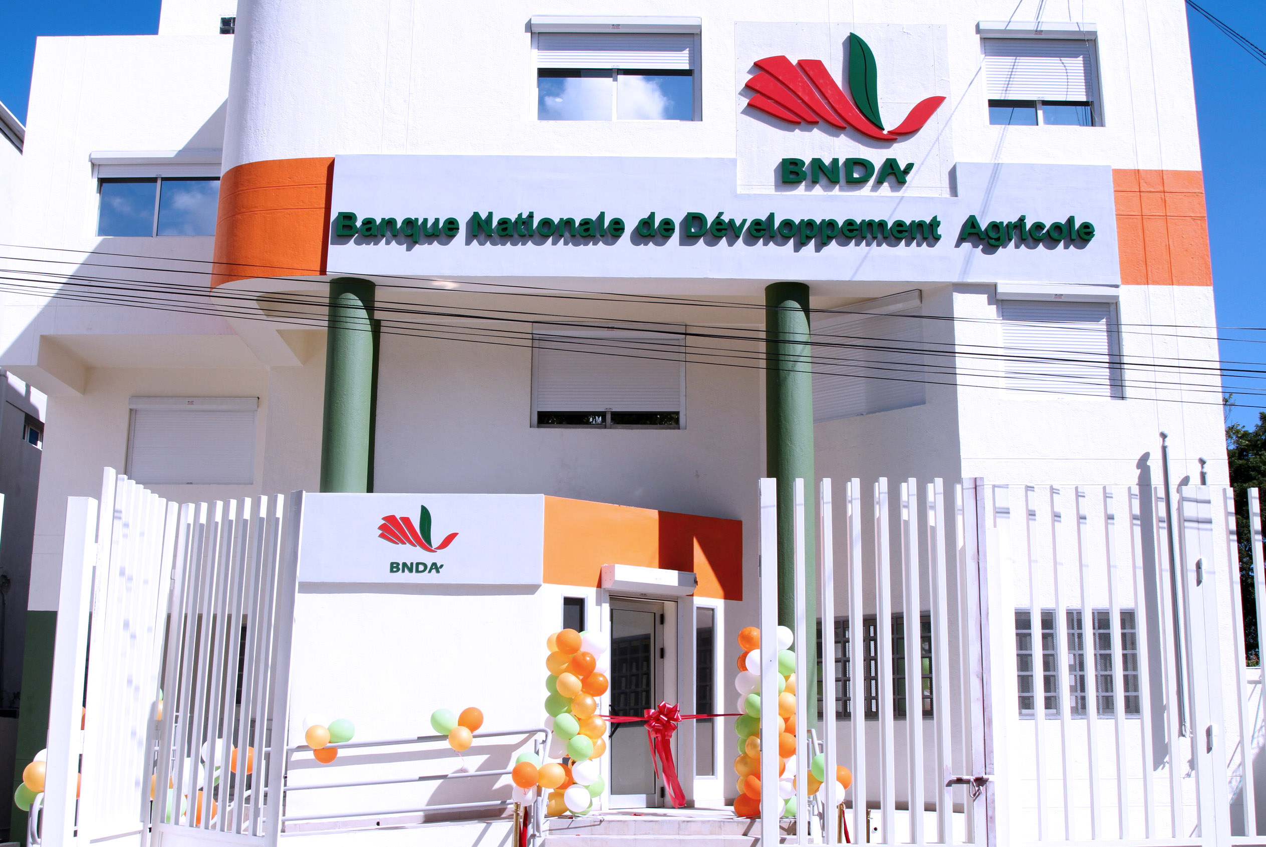 Exterior shot of a white and orange building with the sign Banque Nationale de Developpment Agricole