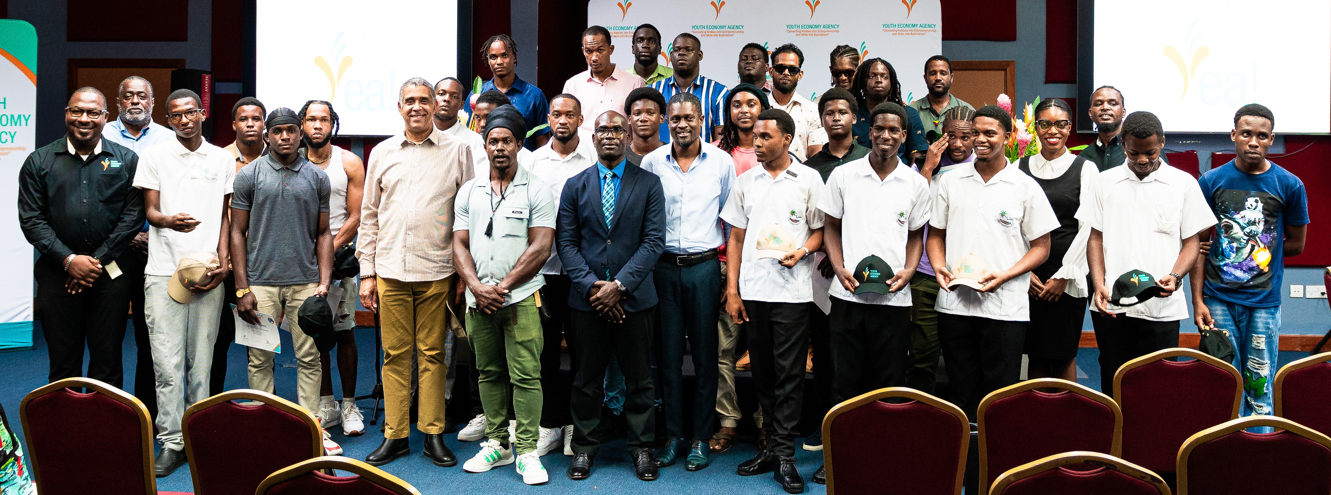 large group of predominantly male participants standing in front of a stage at an indoor venue