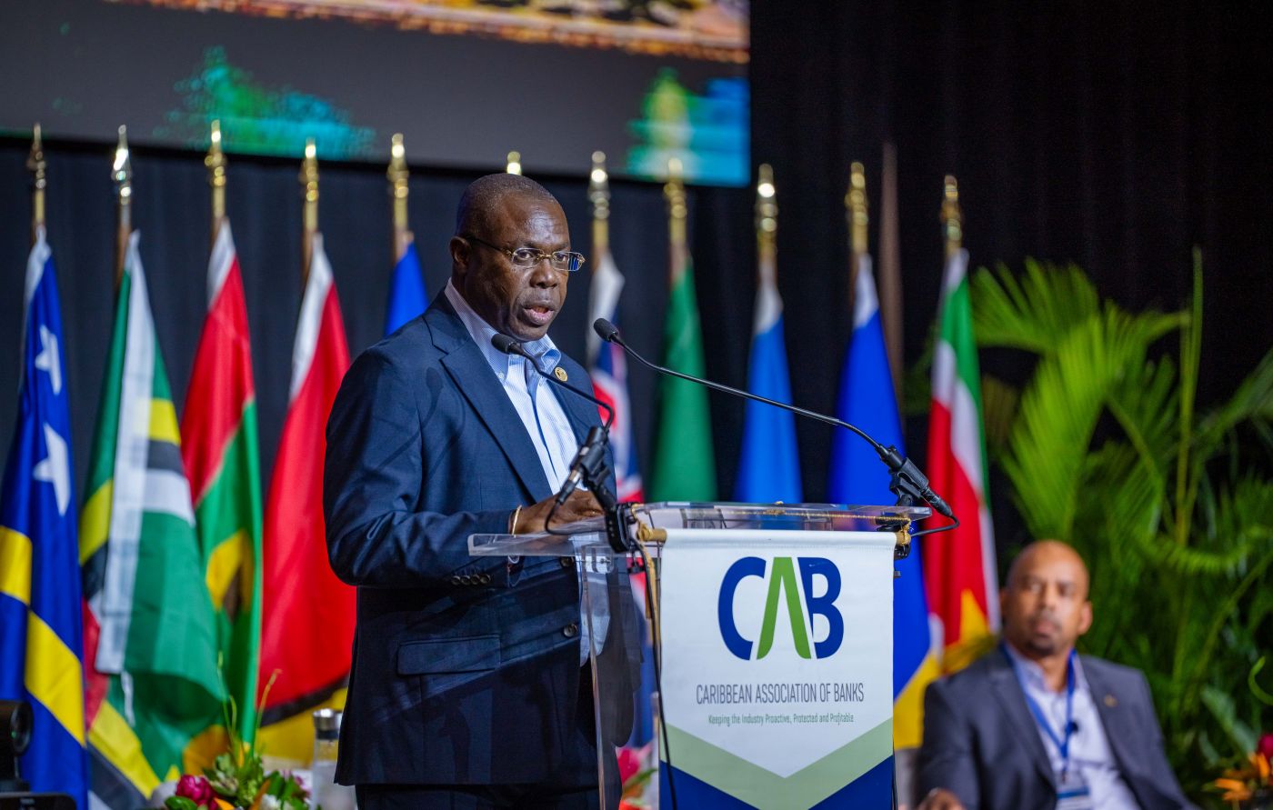 Dr Isaac Solomon in business suit standing at a branded lectern delivering remarks on stage 