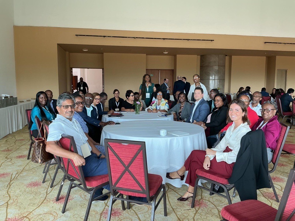 group of procurement professionals seated around two large round tables looking ahead and smiling