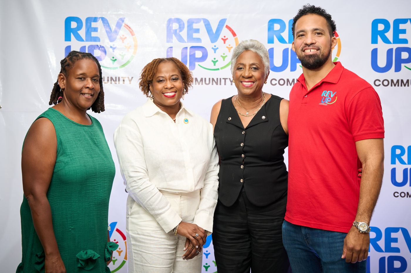 Three black women and one black man standing in a row looking ahead and smiling 