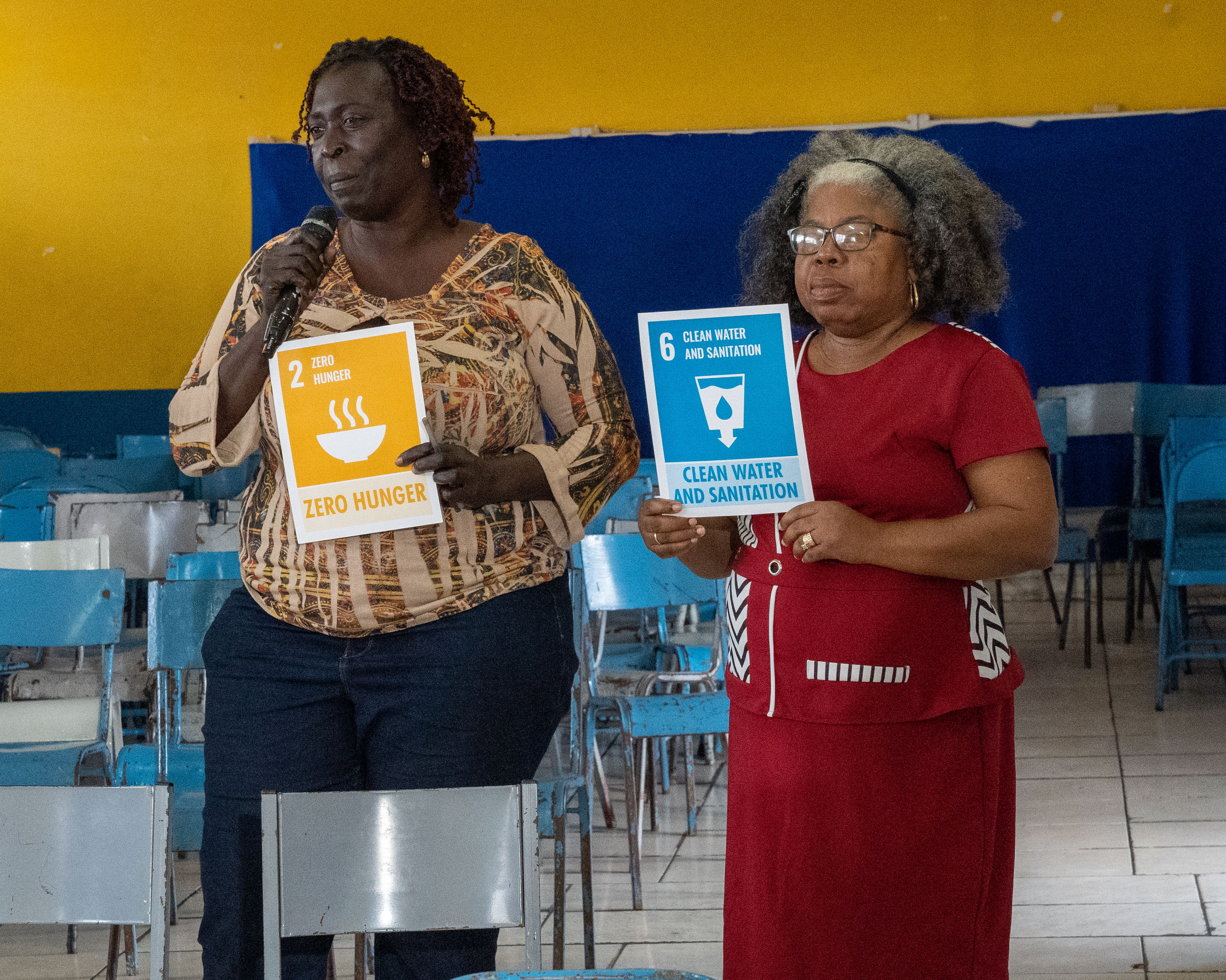 Two participants in a Basic Needs Trust Fund workshop hold tiles representing their priority Sustainable Development Goals