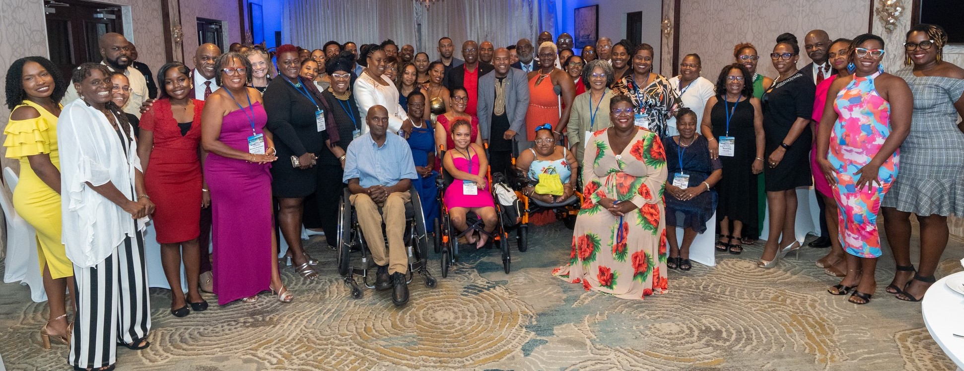A group of disabled persons in elegant colourful clothing in a ballroom. 