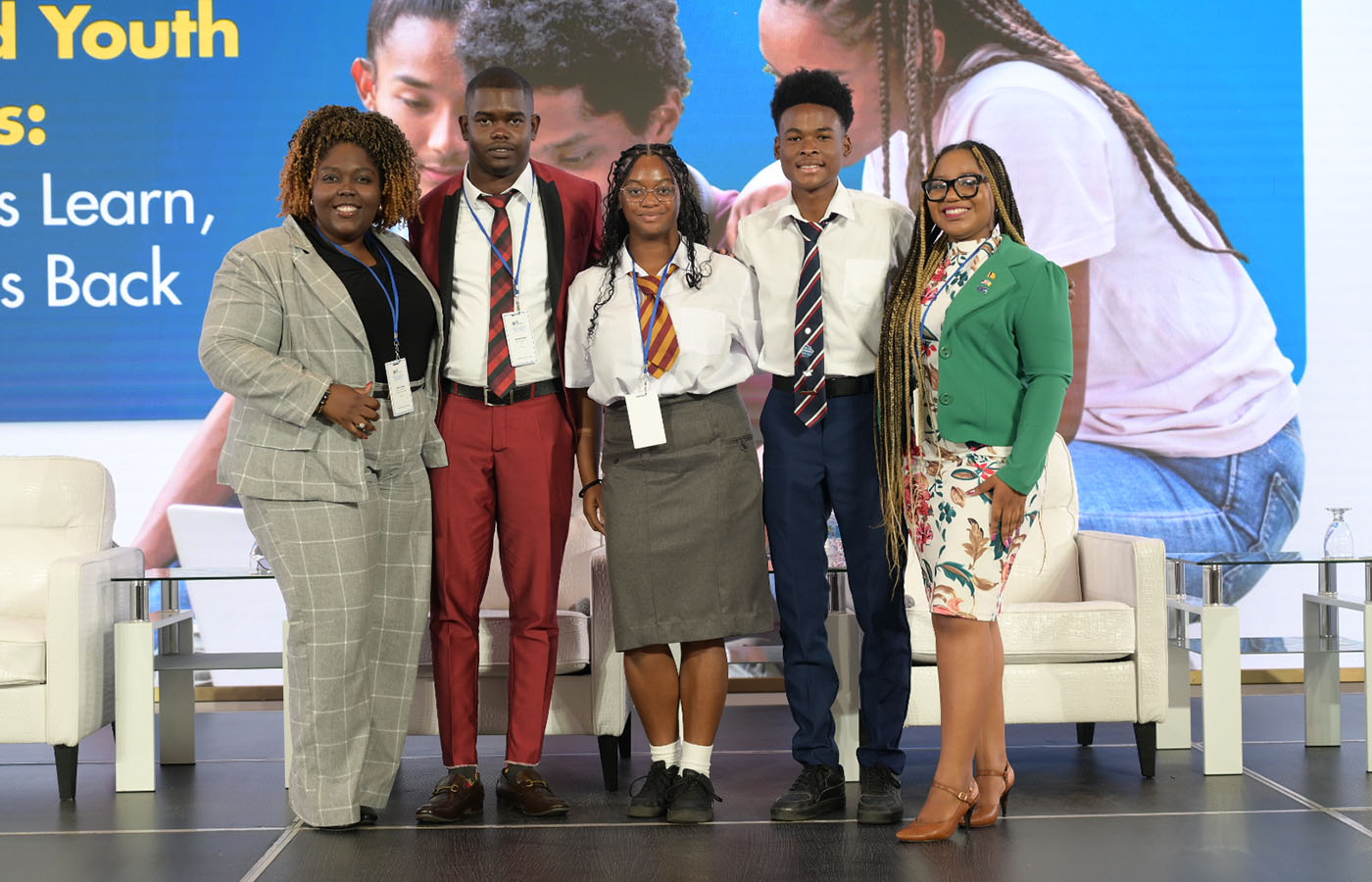 Group of students and educators posing on stage at a youth education symposium.