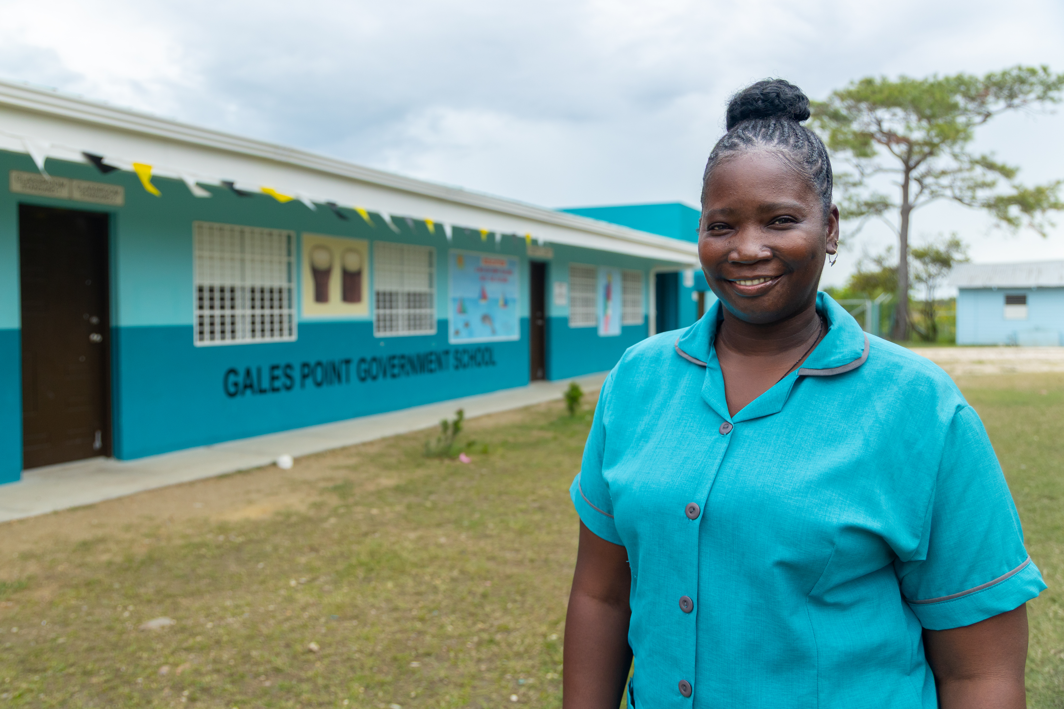 A black woman standing in the yard outside of a school.