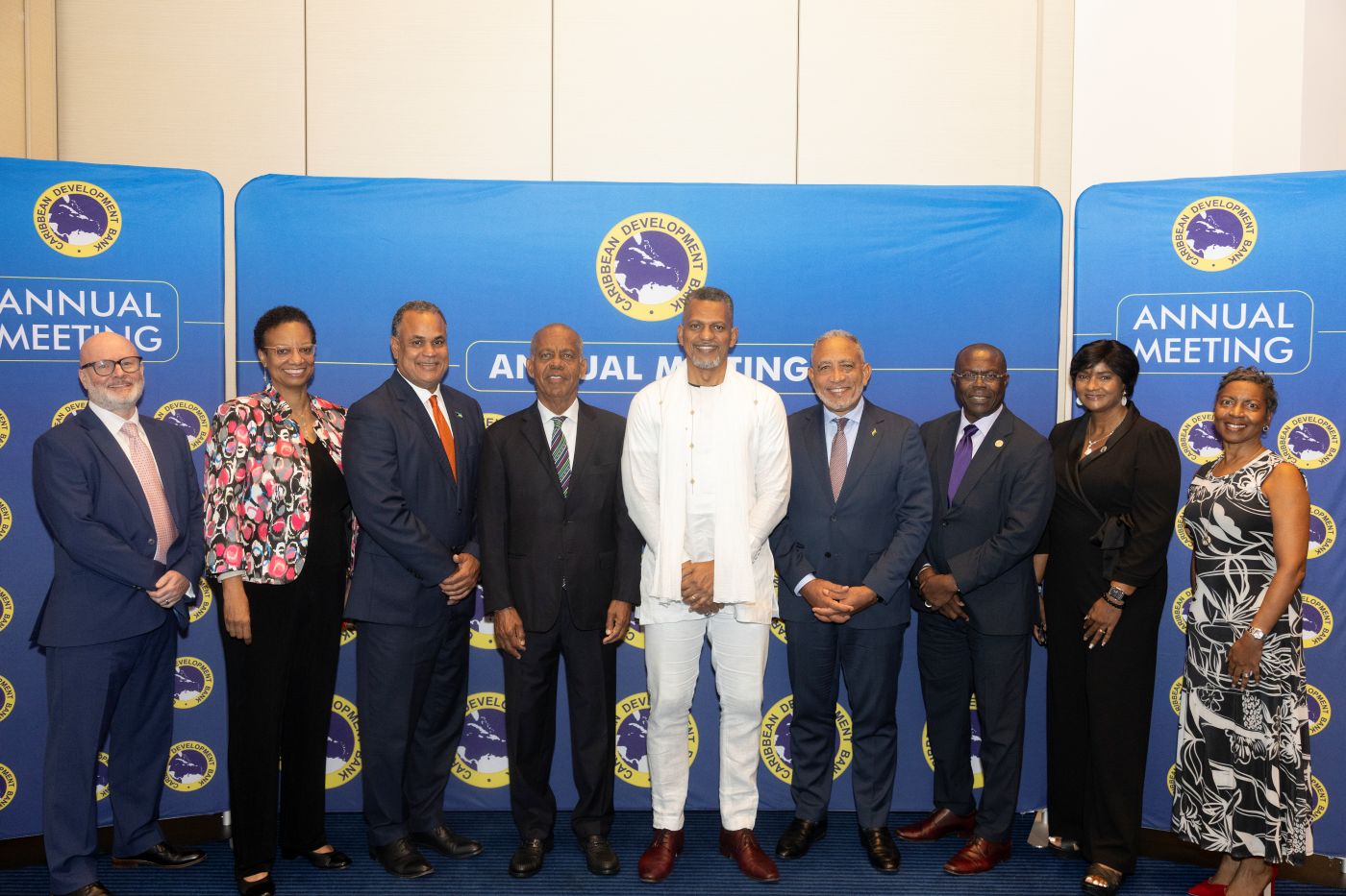 a row of persons standing in formal attire ahead of a bright blue and yellow backdrop