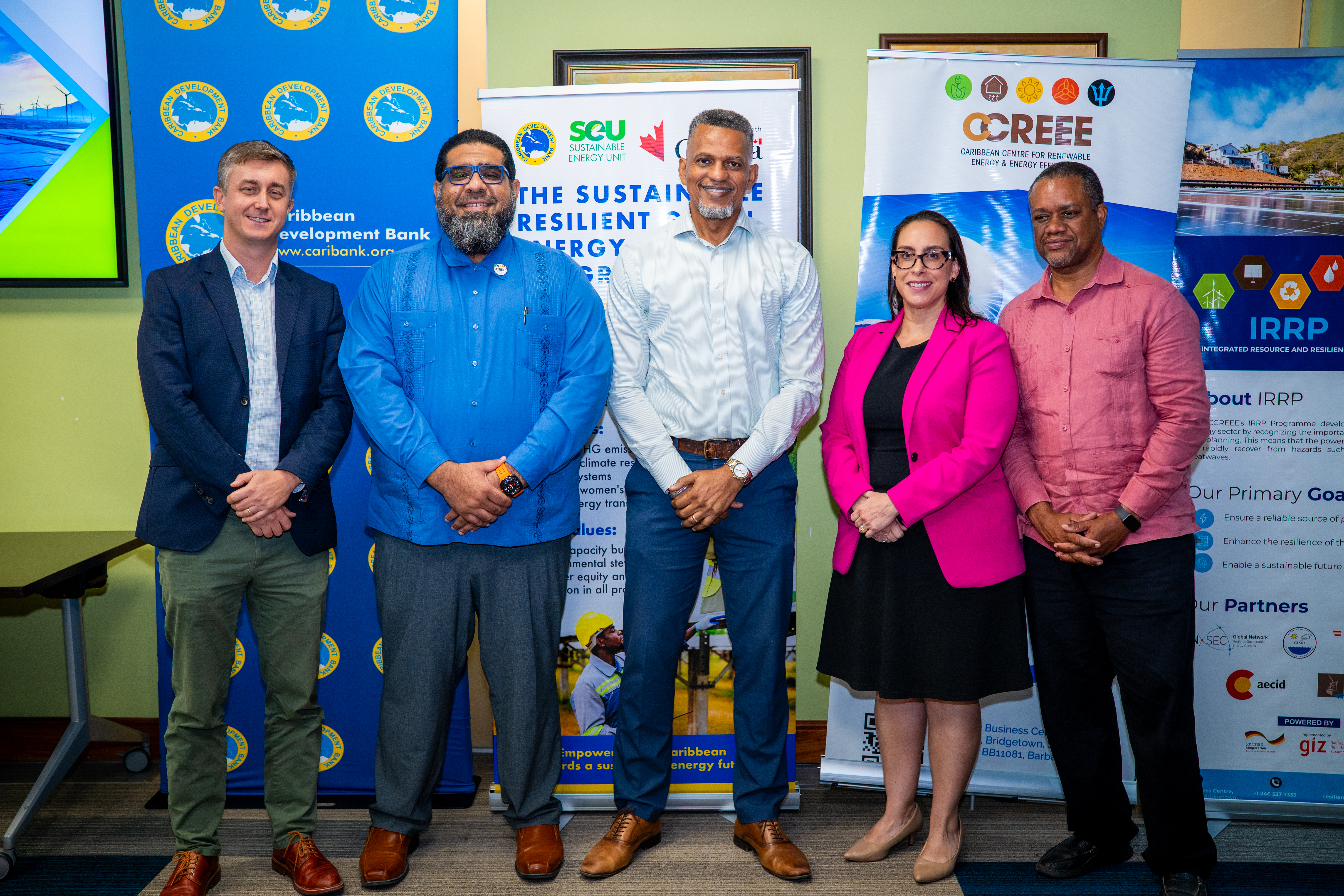 Five people stand in front of promotional banners at launch of new renewable energy project