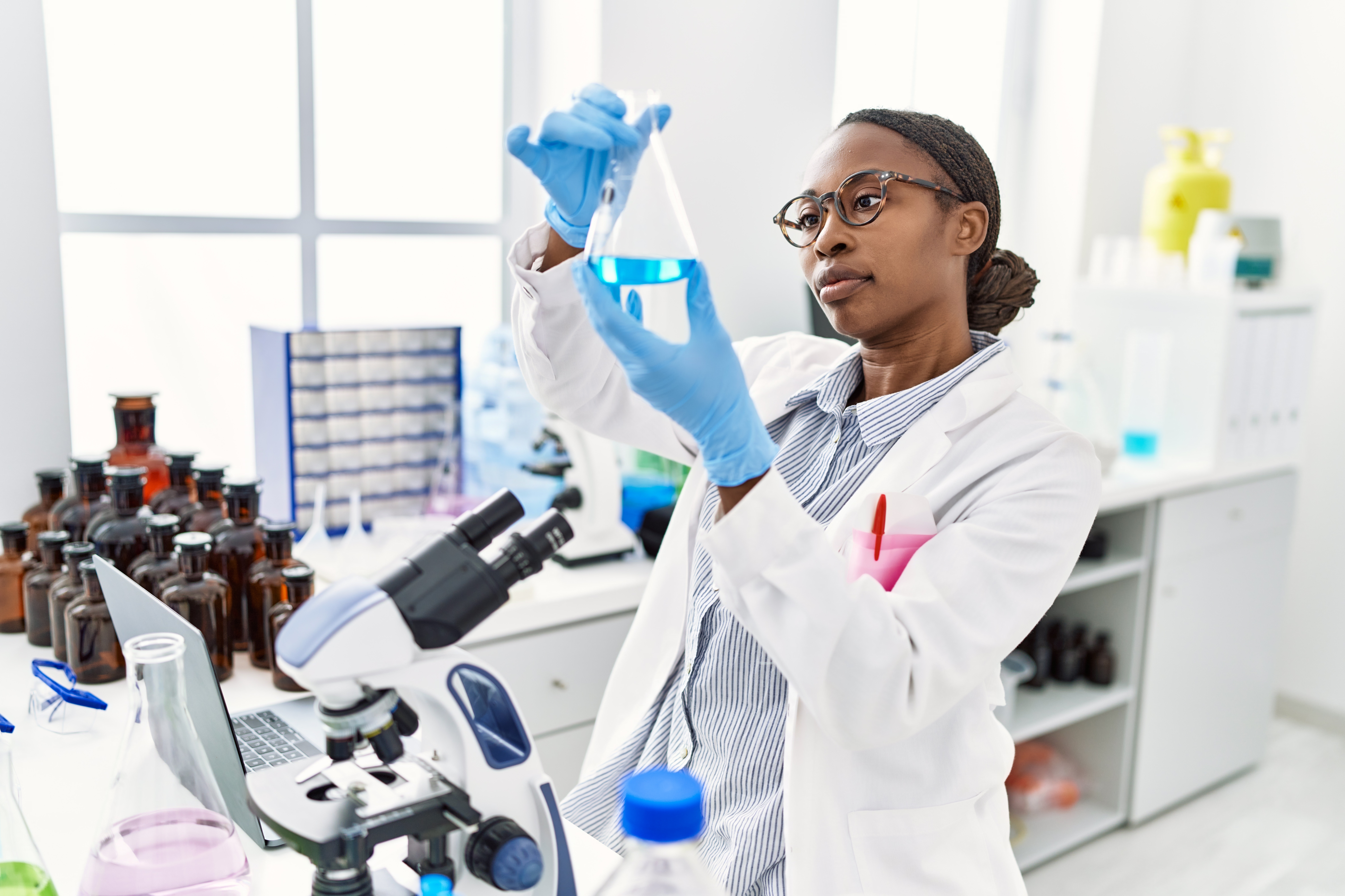 Woman looks at solution in a bottle in lab