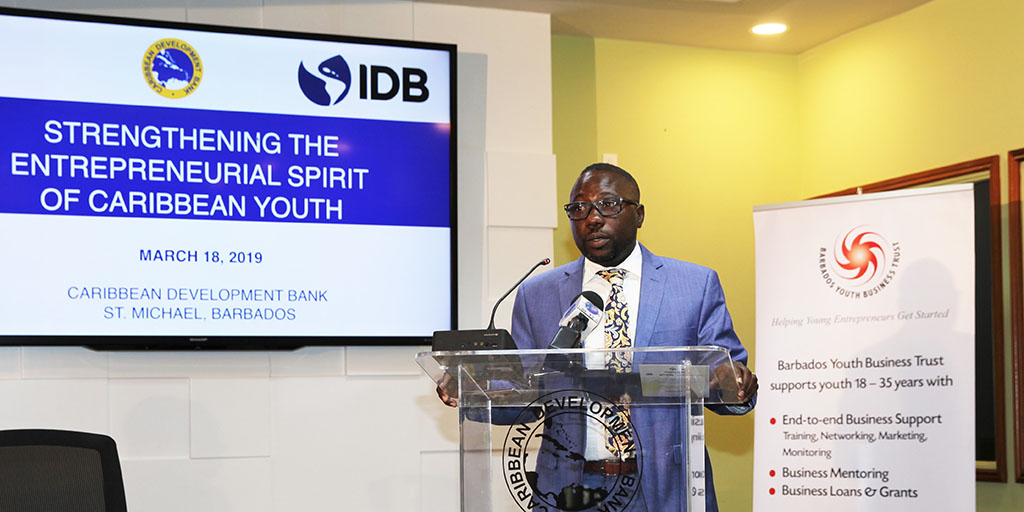 Barbados’ Minister of Small Business, Entrepreneurship and Commerce, Honourable Dwight Sutherland at lectern in blue suit with white shirt