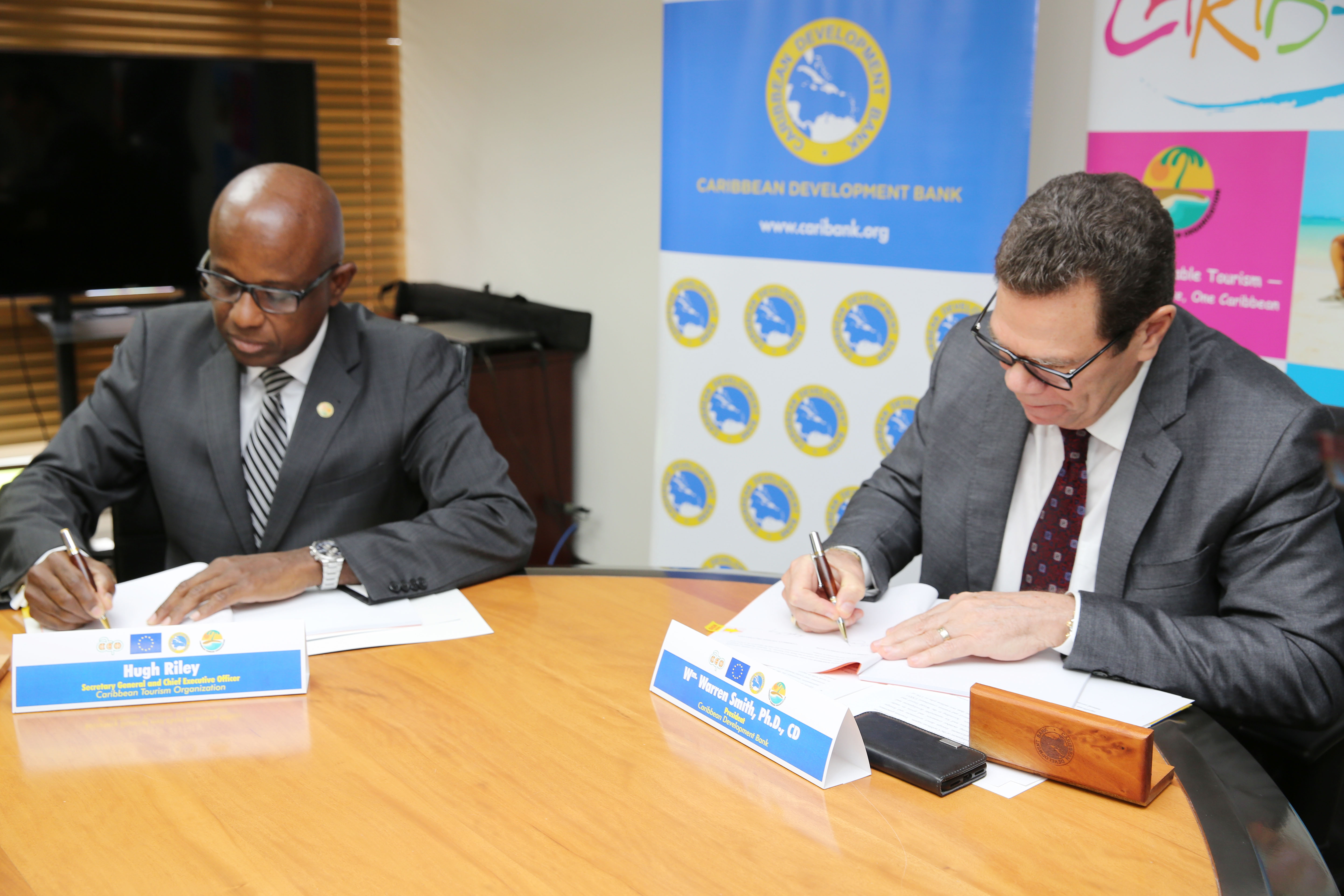 Hugh Riley, Secretary General, CTO (left) and Dr. Wm. Warren Smith, President, CDB (right) sign the agreement for the project, which aims to increase the Caribbean tourism sector’s resilience to natural hazards and climate related risks.
