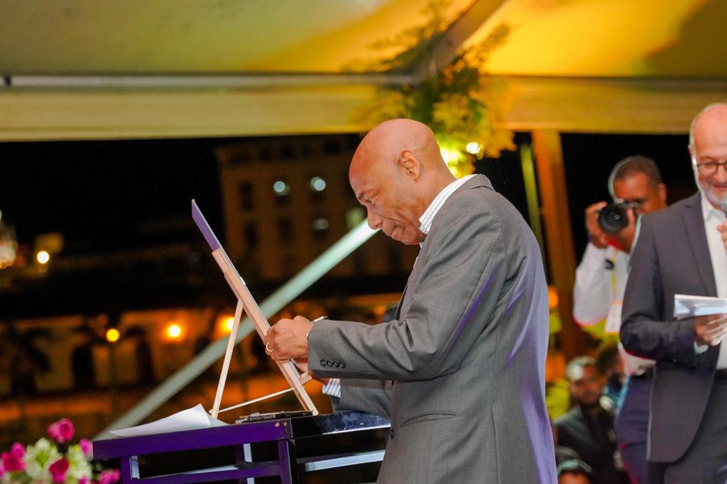 gentleman in dark suit signing a large printed declaration