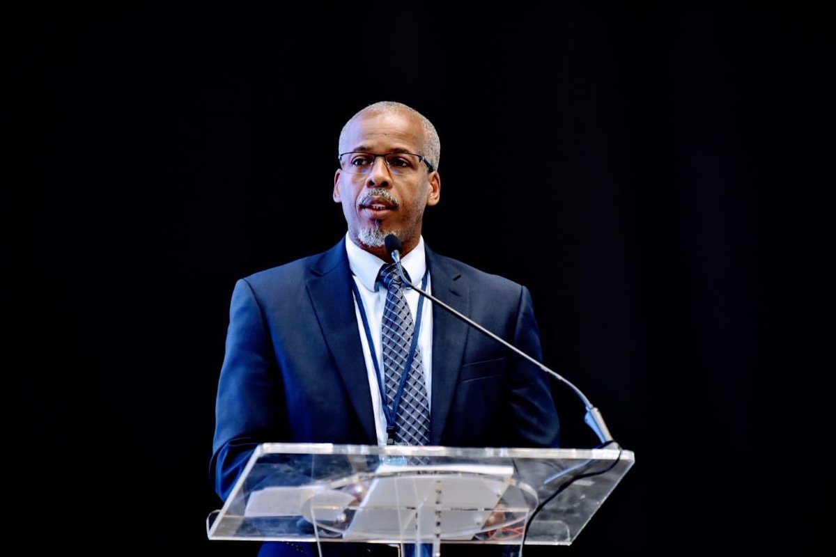 Luther St. Ville in dark suit with white shirt at lectern