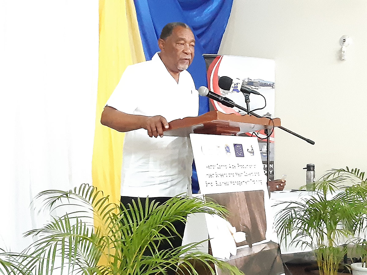 older gentleman in white shirt and black slacks standing at a wooden lectern