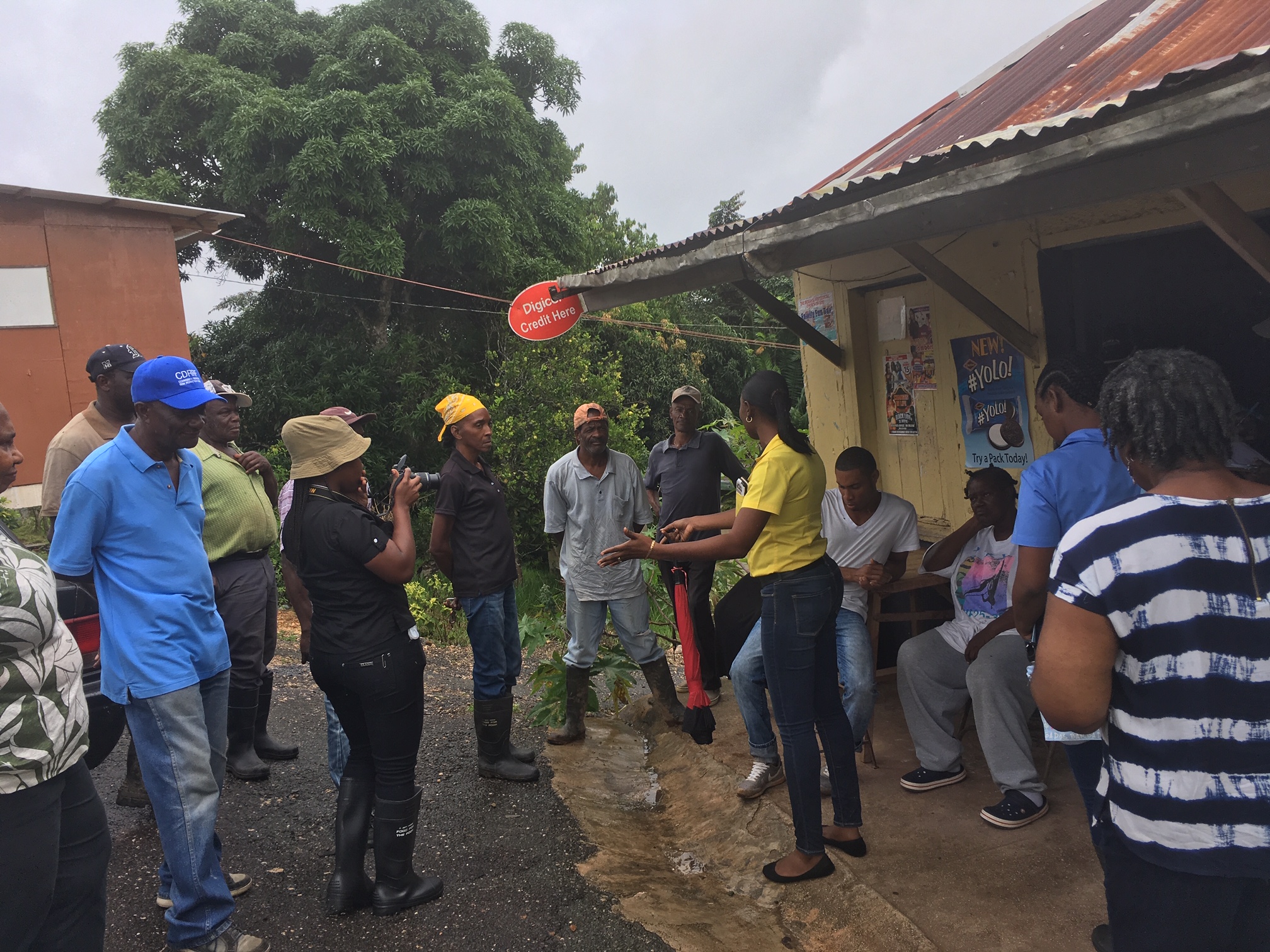 group of male and female farmers standing outside a rural shop talking