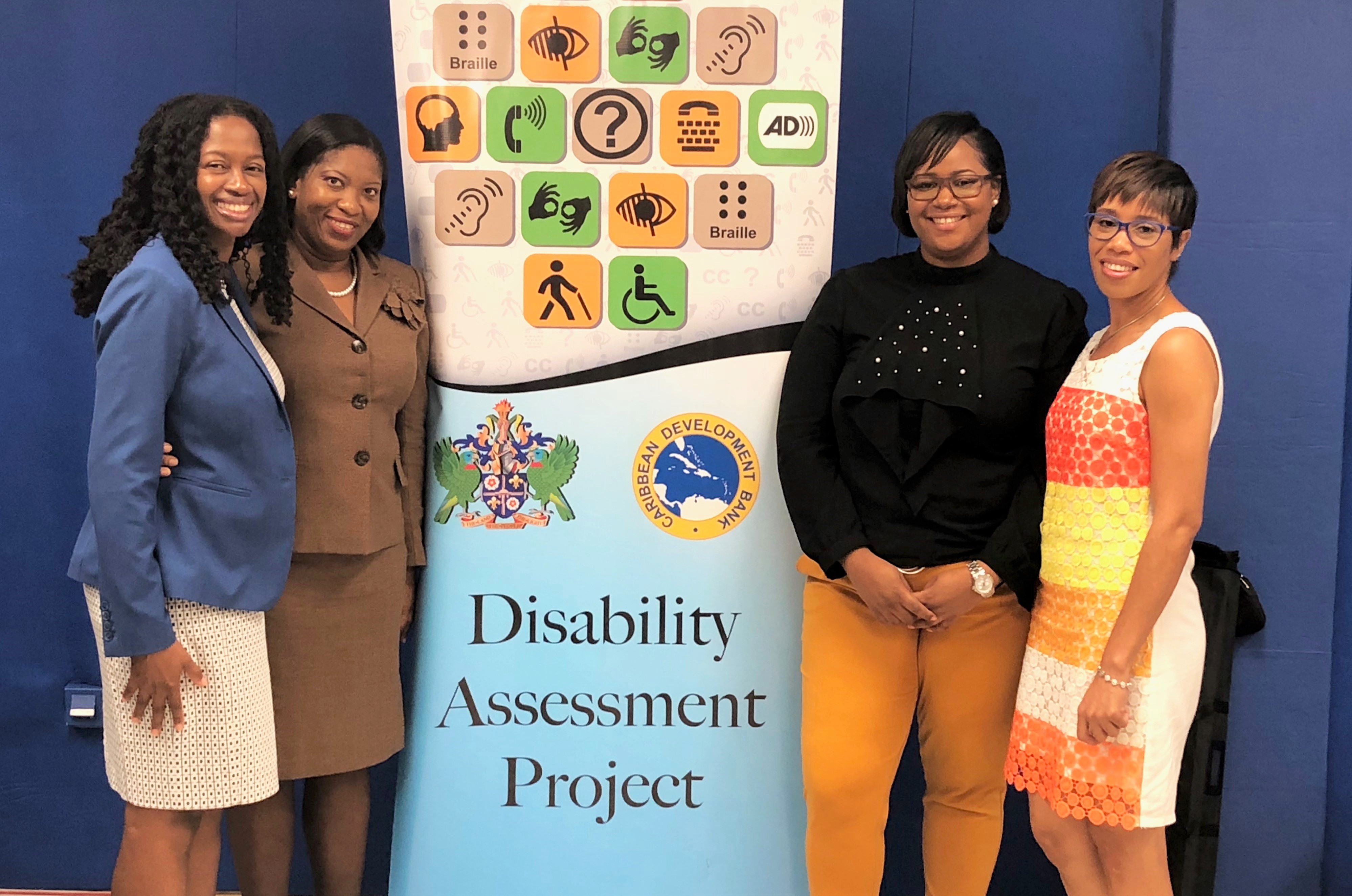 Four women flanking colourful pull up banner with disability icons