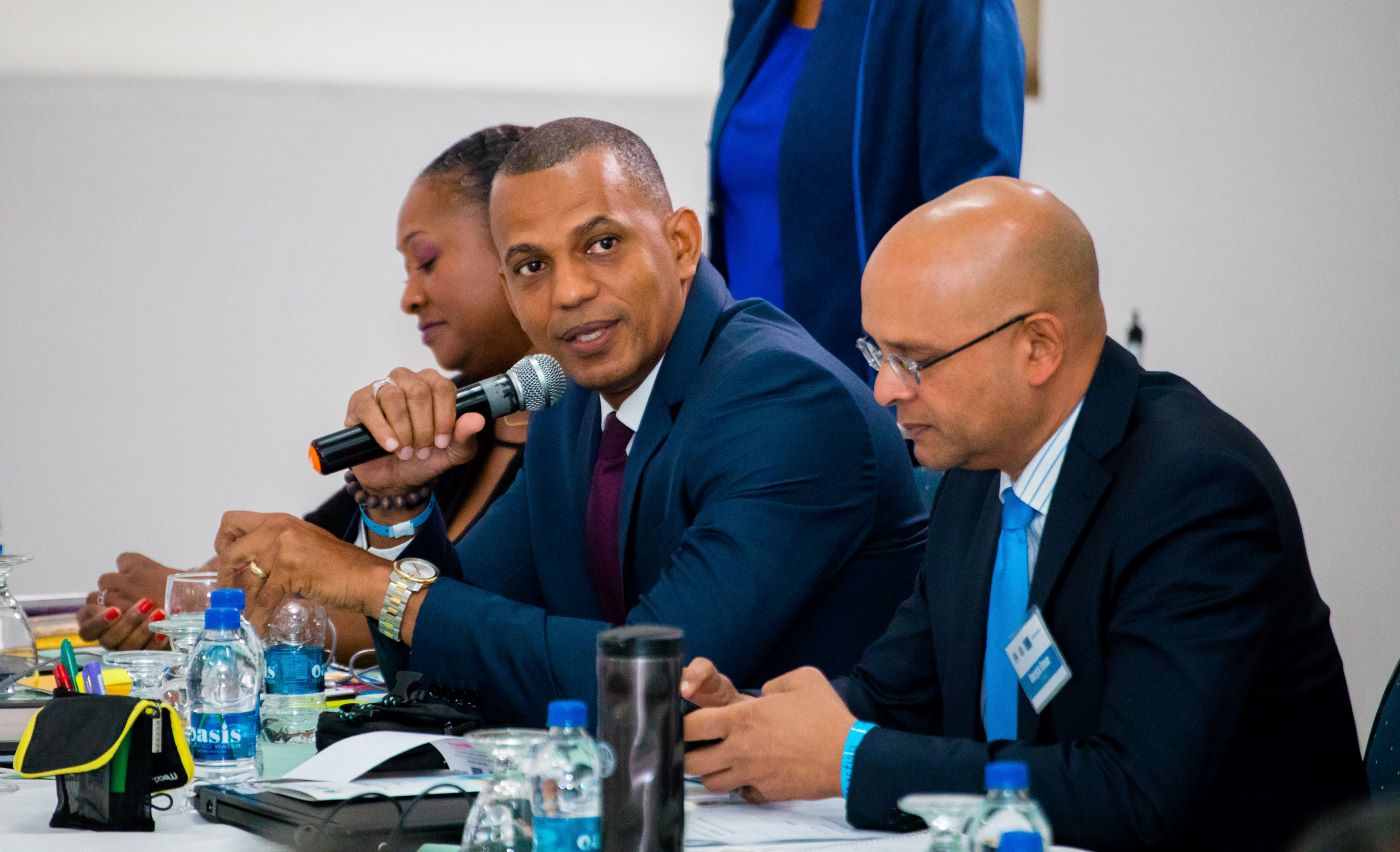 Daniel Best sitting at head table speaking into microphone.