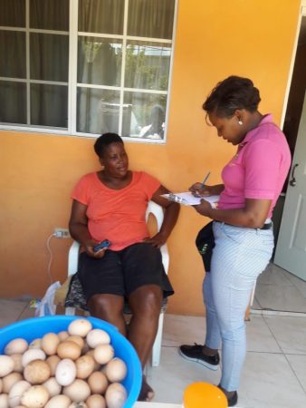 standing lady in pink shirt interviewing seated woman