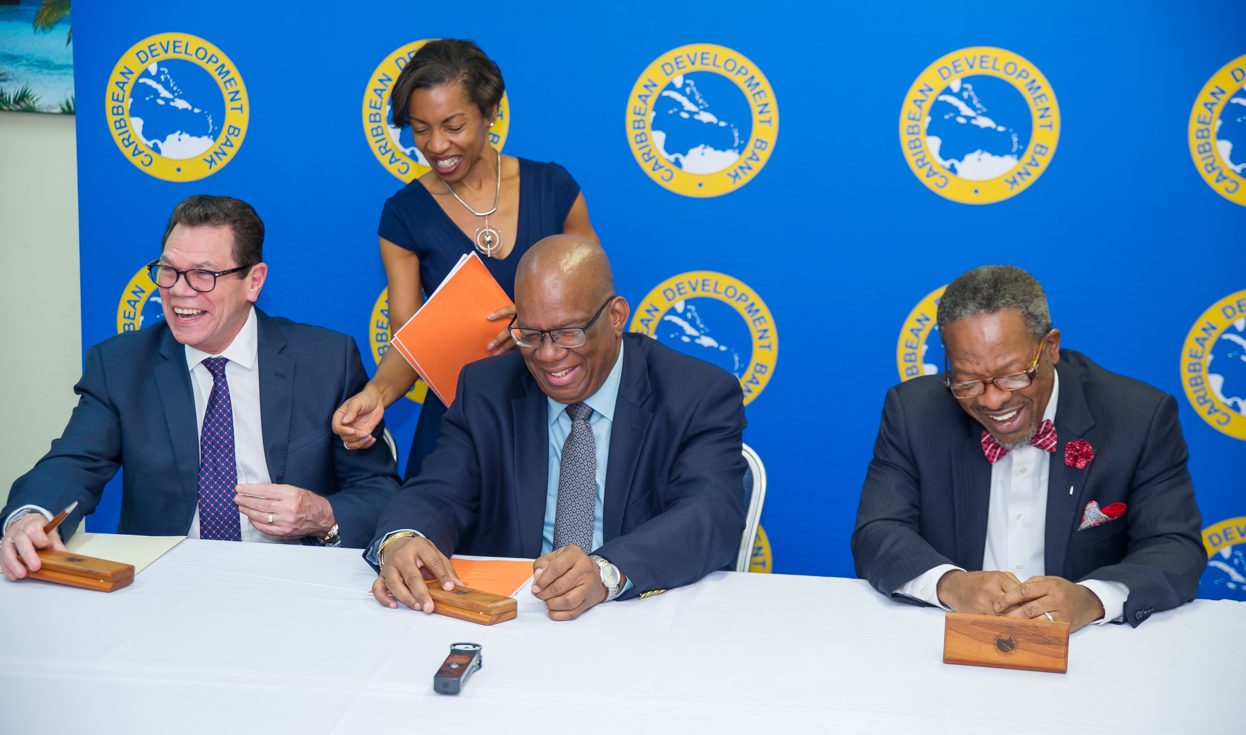 (L-R) Dr. Wm. Warren Smith, President, CDB, Hon. Winston Jordan, Minister of Finance, Guyana; and Ivelaw Lloyd Griffith, Vice-Chancellor of the University of Guyana prepare to sign the grant agreement on May 29. Assisting is Diana Wilson Patrick (standing), General Counsel, CDB.