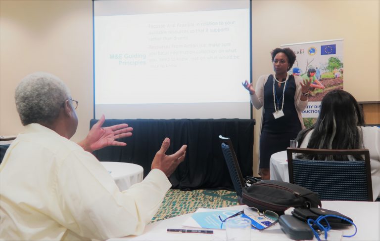 standing workshop presenter at the front of the room speaking with a seated participant