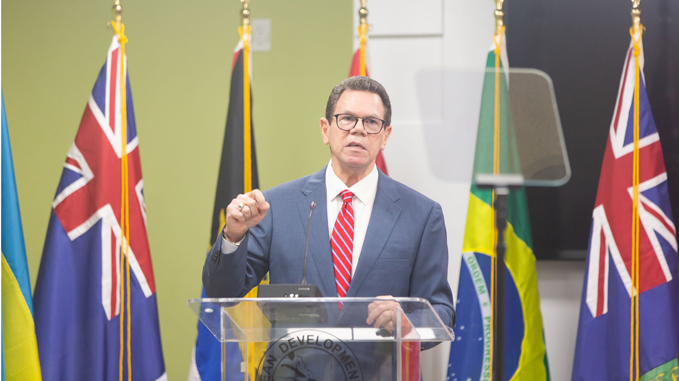 CDB President Dr Wm Warren Smith wearing blue suit and red tie, standing at a transparent lectern