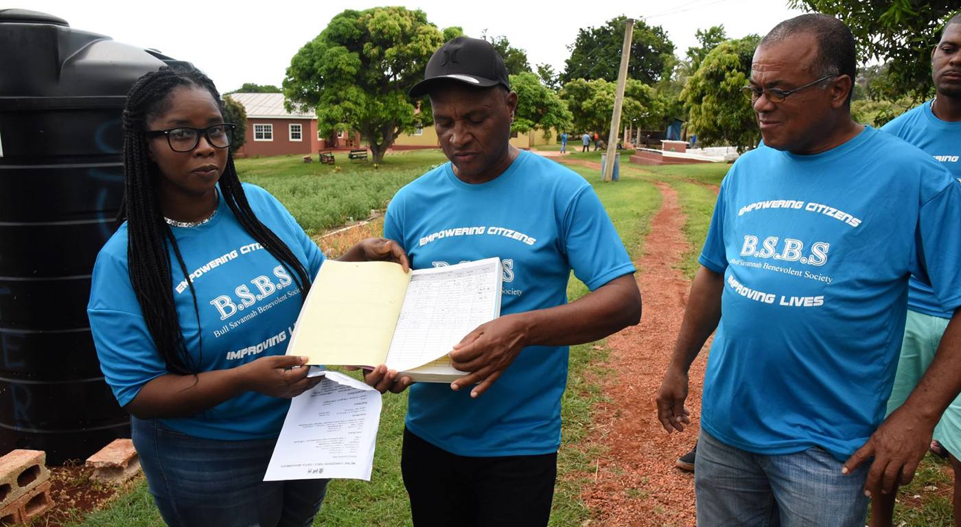 President of the Bull Savannah farmers’ group, Tracey Powell, showing a logbook with two group members