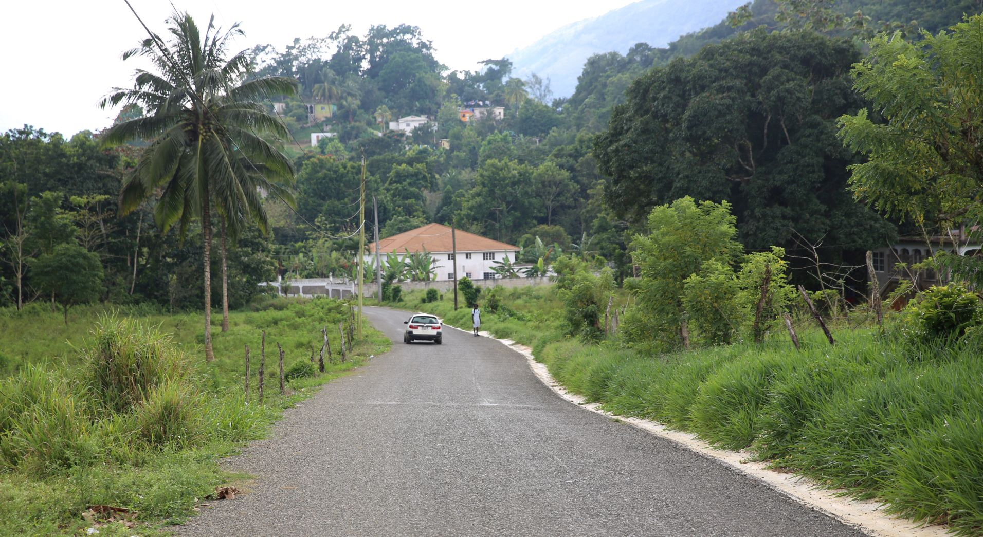 A white car and a pedestrian are on the main road of Grierfield