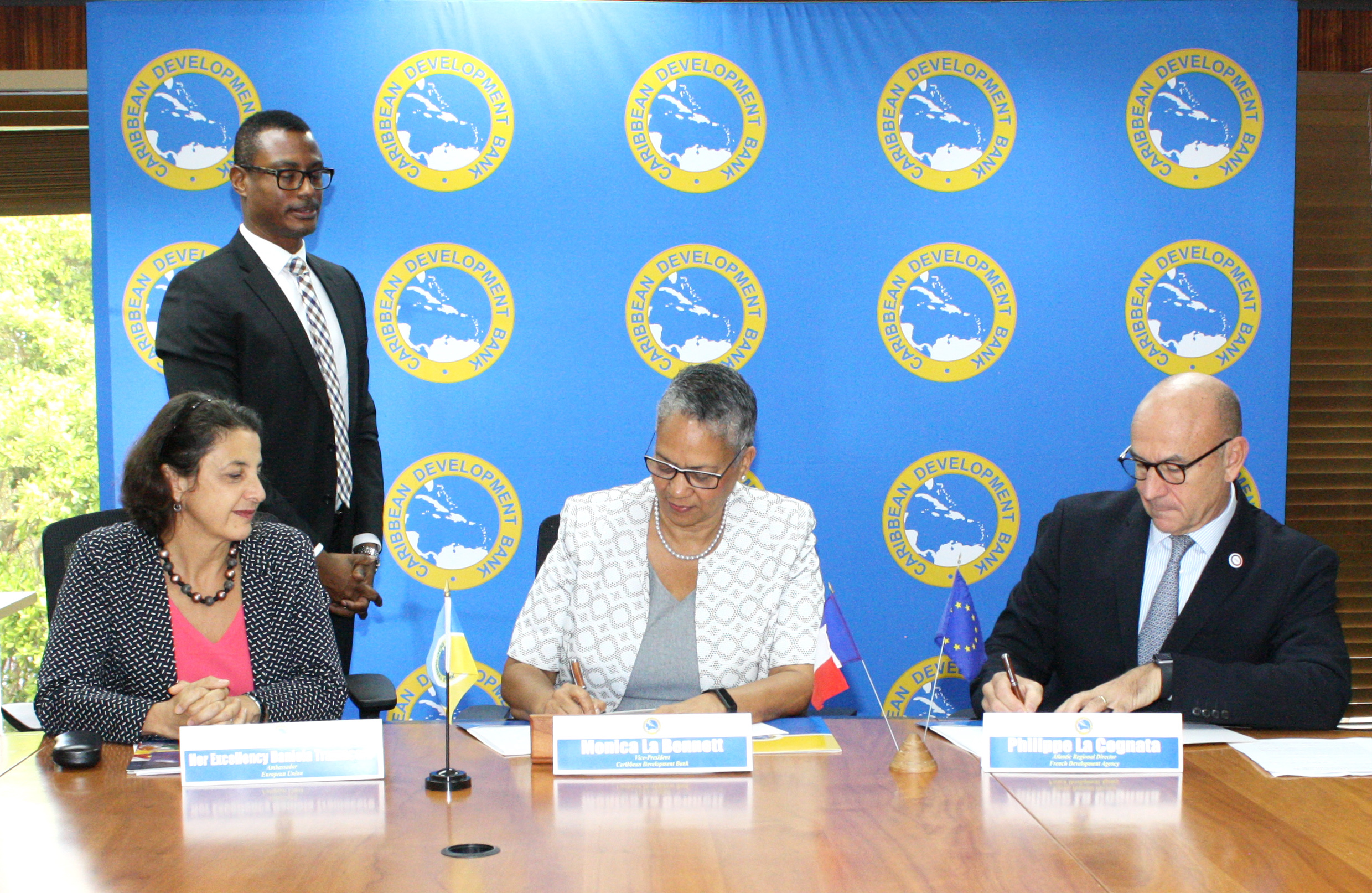 Vice-President (Operations) of the Caribbean Development Bank, Monica La Bennett (center) and Philippe La Cognata, Atlantic Regional Director, Agence Française De Développement (right) sign the finance agreement. At left, Ambassador Daniela Tramacere, Head of the European Union Delegation to Barbados, the Eastern Caribbean, OECS and CARICOM/CARIFORUM and CDB Senior Legal Counsel Dave Waithe (second from left) look on.
