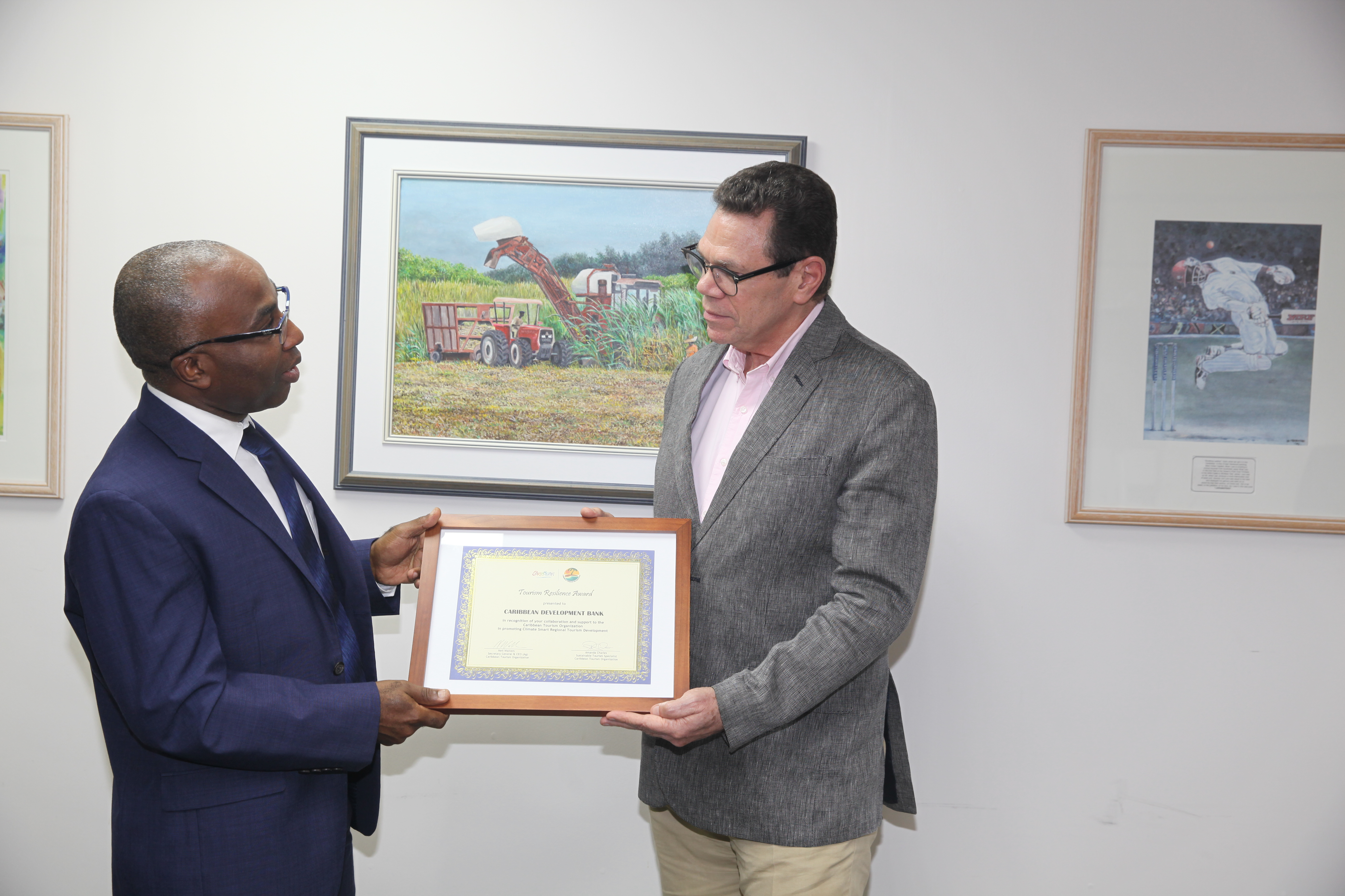 Dr Yves Personna in blue suit presenting award to Dr Warren Smith in grey jacket.